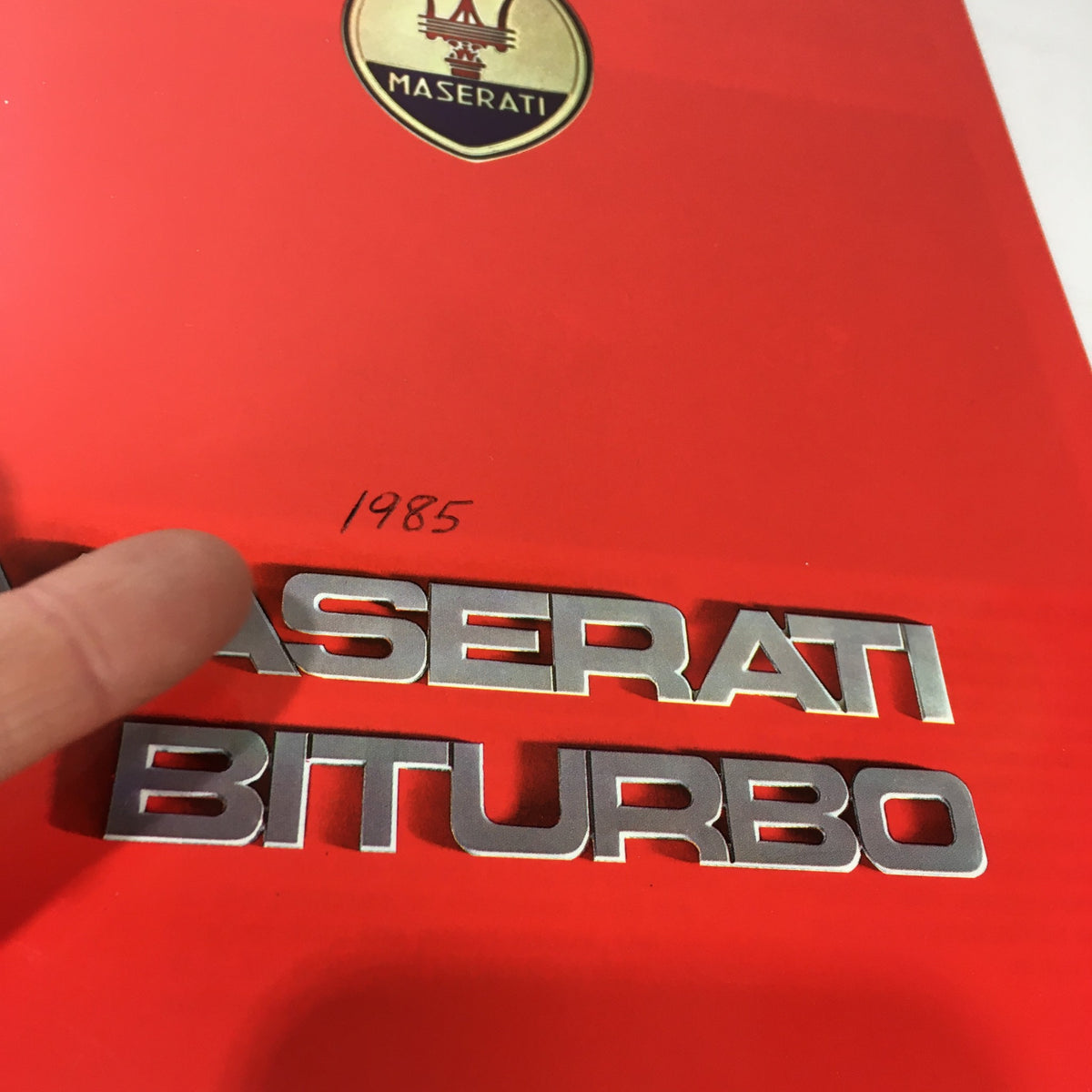 Close-up of the 1985 Maserati Biturbo Dealership Car Auto Brochure Catalog cover showing the Maserati logo with the year 1985 and the model name Biturbo.