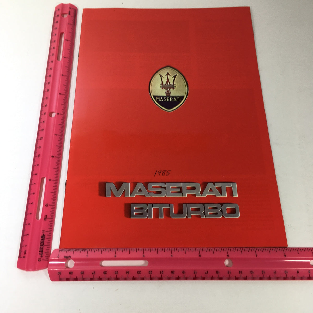 1985 Maserati Biturbo Dealership Car Auto Brochure Catalog front page displaying the Maserati logo and model name with a ruler for size reference.