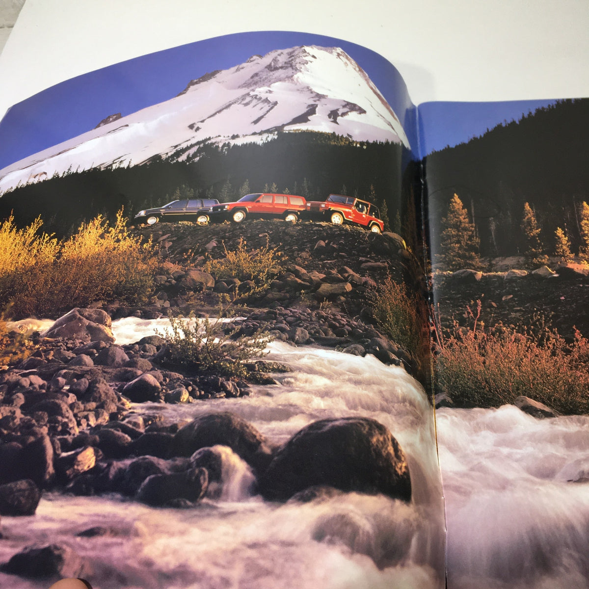 Interior page of the 1995 The Jeep Book Dealership Car Auto Brochure Catalog showcasing Jeeps on rocky terrain with a snow-capped mountain backdrop.