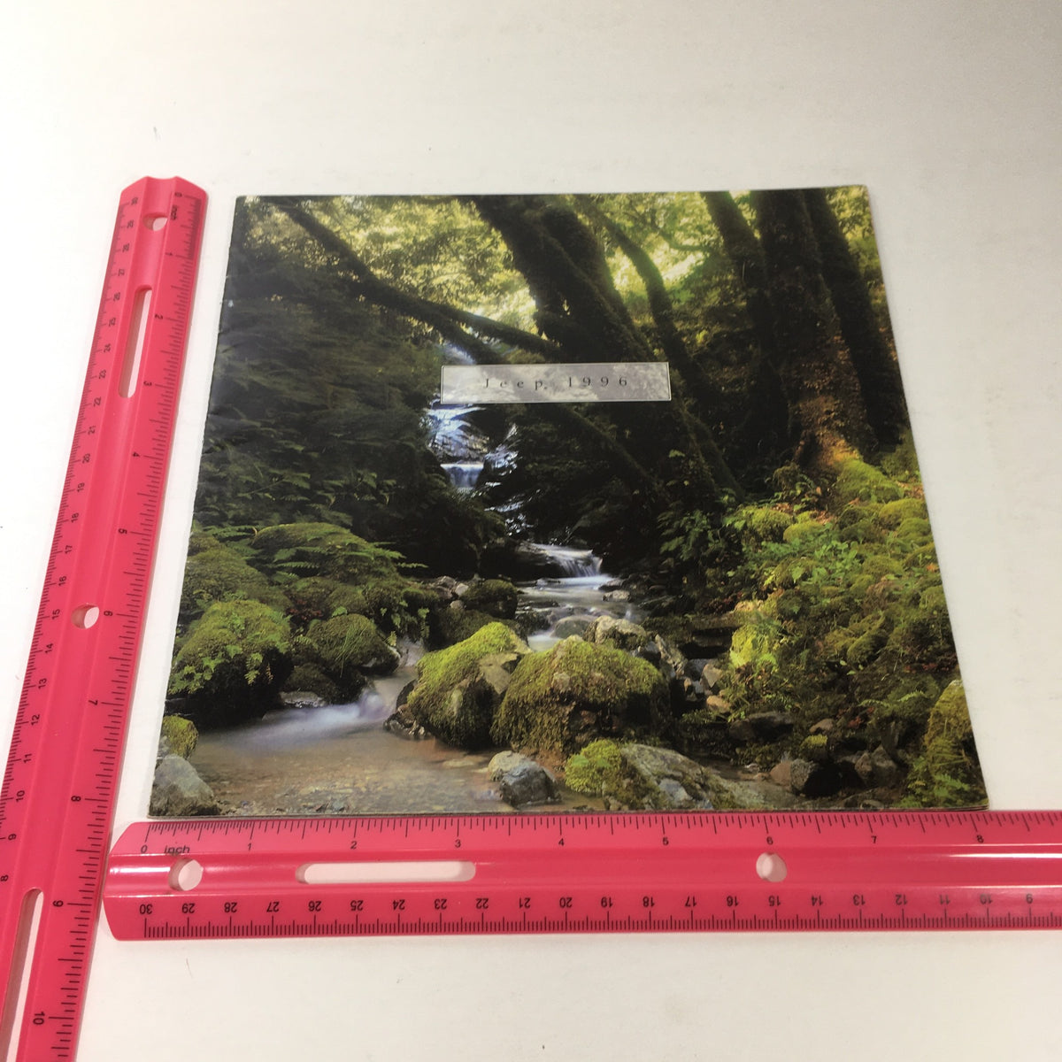 Close-up of a creek surrounded by mossy rocks featured on the cover of the 1996 Jeep TJ Wrangler and CJ-2A dealership brochure.