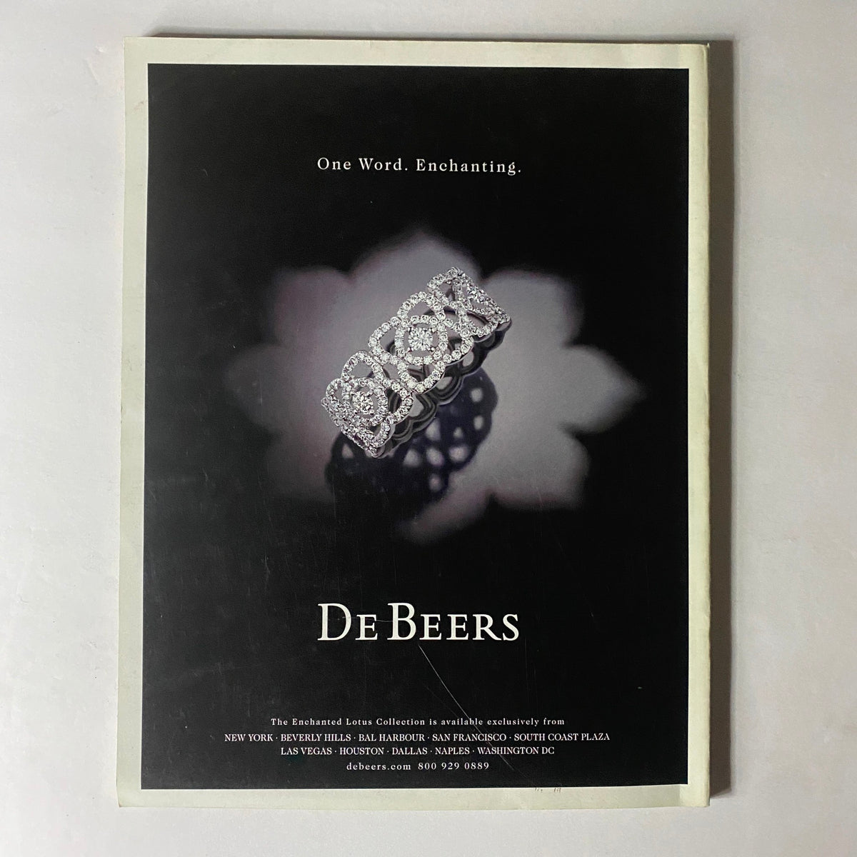 Advertisement for De Beers jewelry in W Magazine February 2010 illustrating a stunning diamond ring with the tagline 'One Word. Enchanting.'