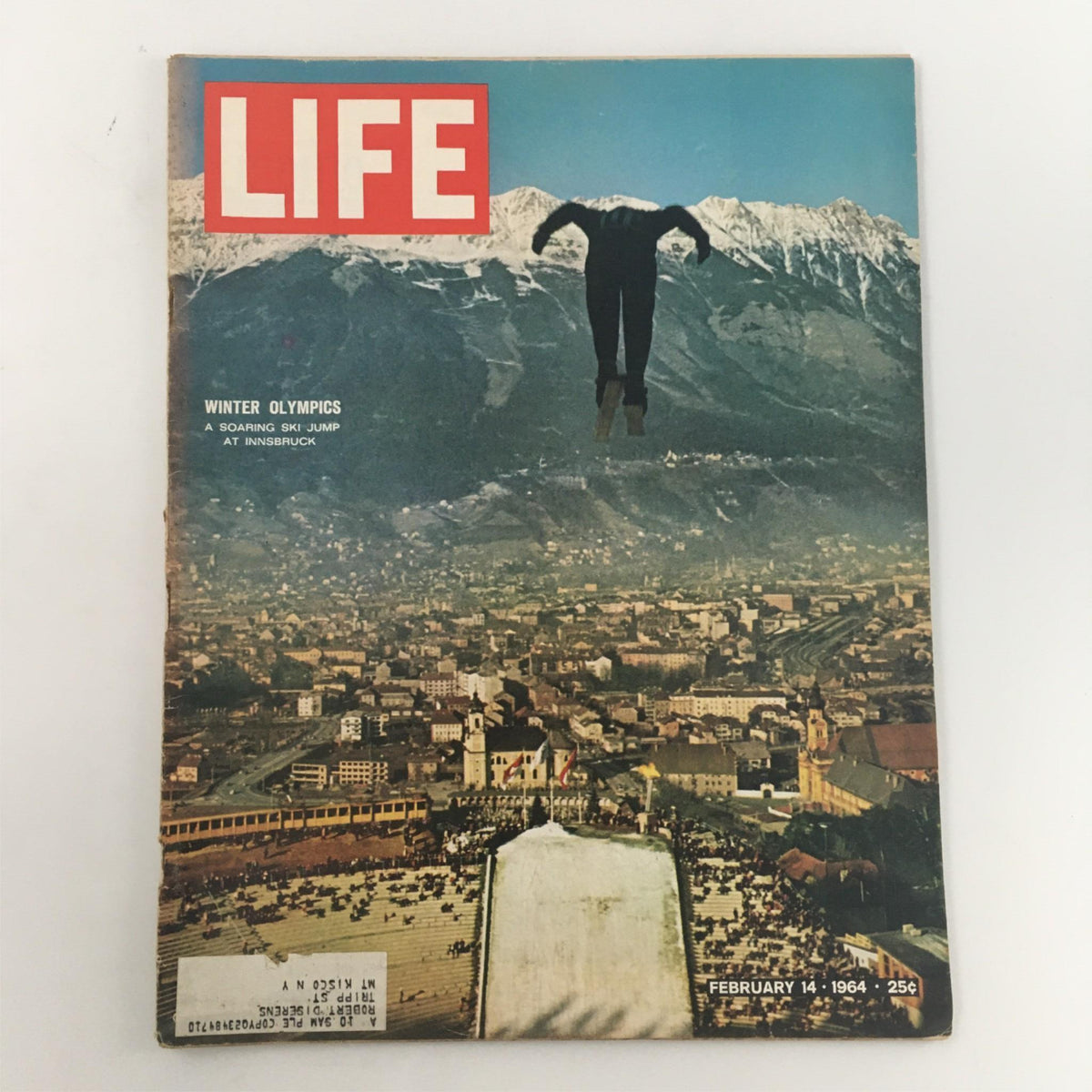 Life Magazine February 14, 1964 cover featuring a soaring ski jumper at the Winter Olympics in Innsbruck, showcasing a stunning aerial view of the surrounding mountains and cityscape.