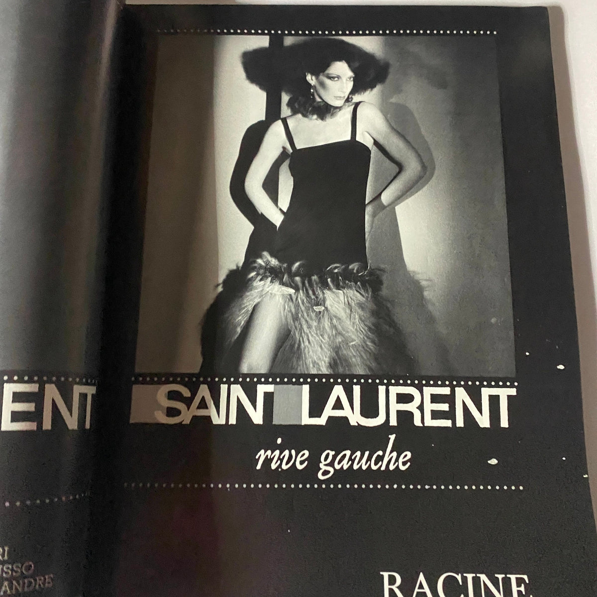 Stylish Saint Laurent advertisement featuring a model in a chic black dress with fur accents, representing 1970s fashion elegance. Vogue Paris Magazine February 1977 Marcie Hunt by Guy Bourdin Cover No Label.