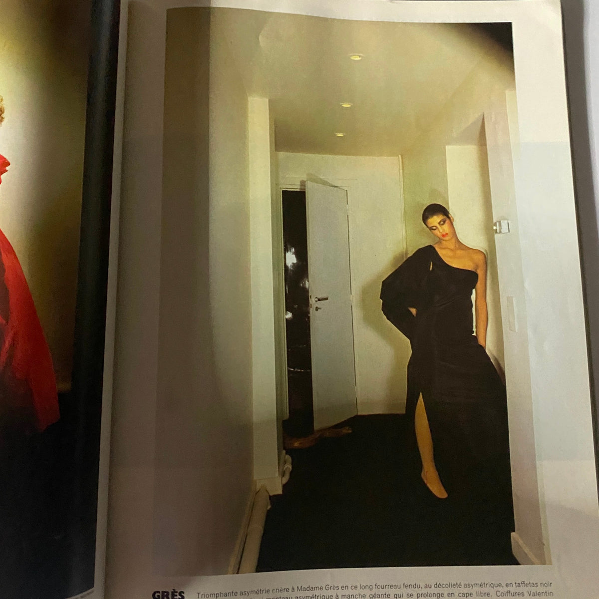 Interior shot featuring a model in a long black asymmetrical gown from the Vogue Paris Magazine September 1976 Dayle Haddon Cover, highlighting the fashion designs of the late 1970s.
