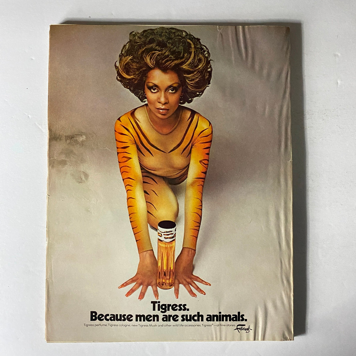 Advertisement from Vogue Magazine December 1975 for Tigress perfume, showcasing a model in a tiger-striped outfit with the tagline 'Because men are such animals'.