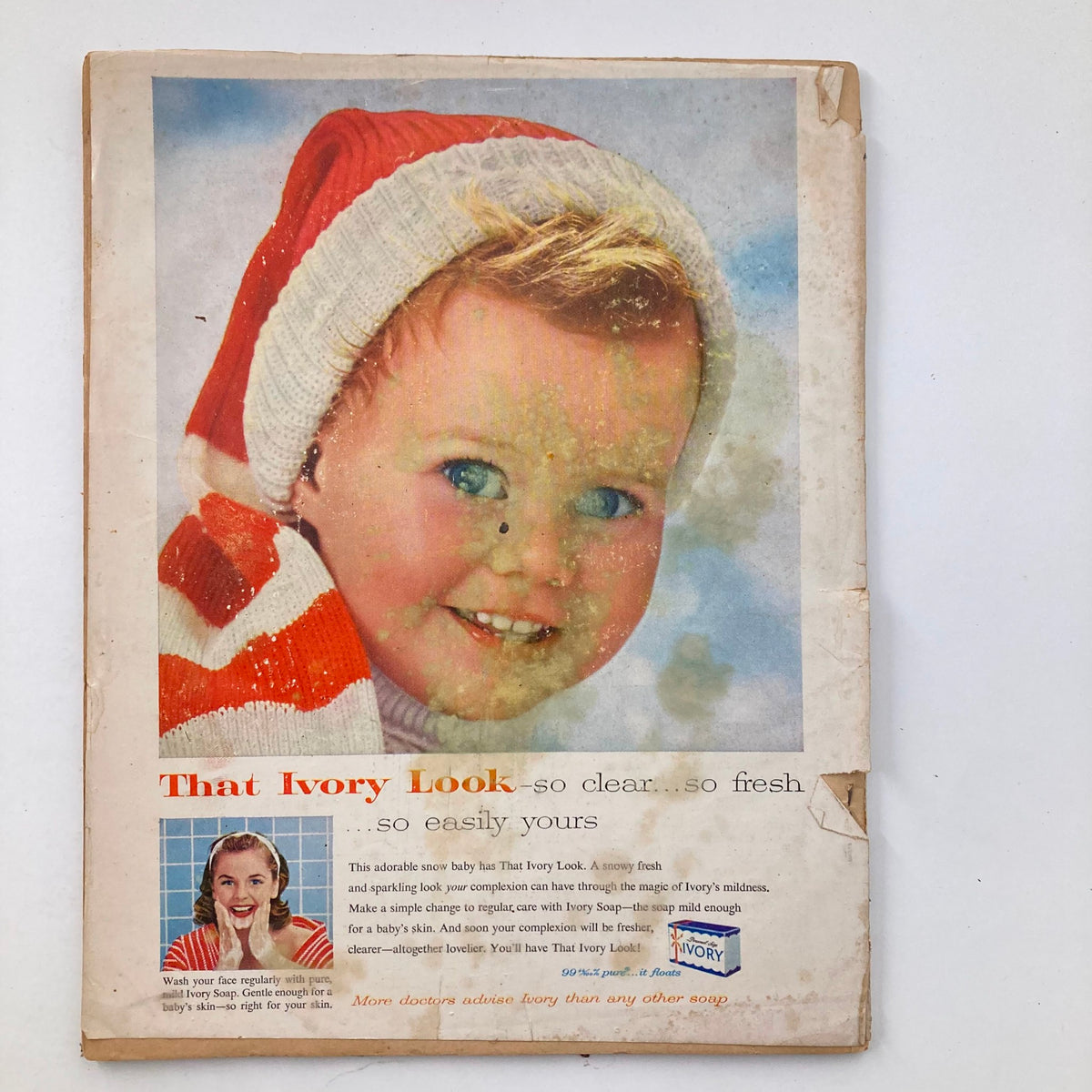 Close-up of a vintage advertisement with a cheerful baby model in a striped outfit and Santa hat, promoting Ivory Soap in the December 1957 issue of VTG Modern Screen Magazine.