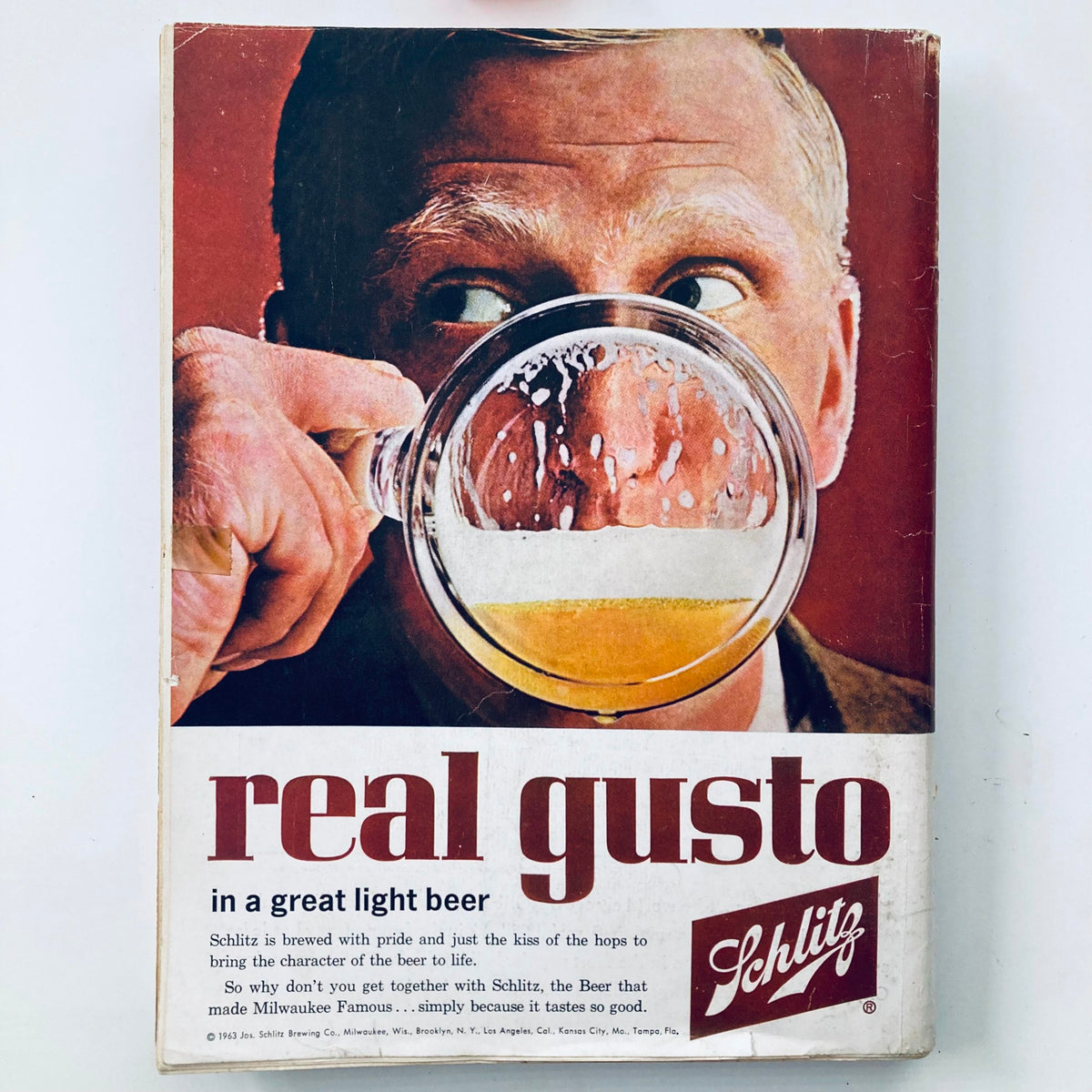 Vintage advertisement from the 1963 Playboy Magazine, displaying a man holding a mug of Schlitz beer with the slogan 'real gusto' prominently featured.