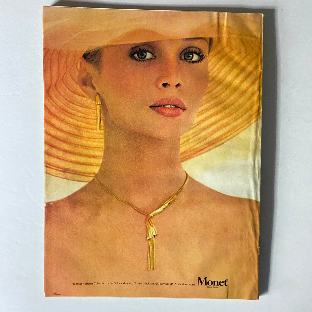 Monet jewelry advertisement from Harper's Bazaar Magazine February 1978 with model wearing elegant accessories and a sun hat.