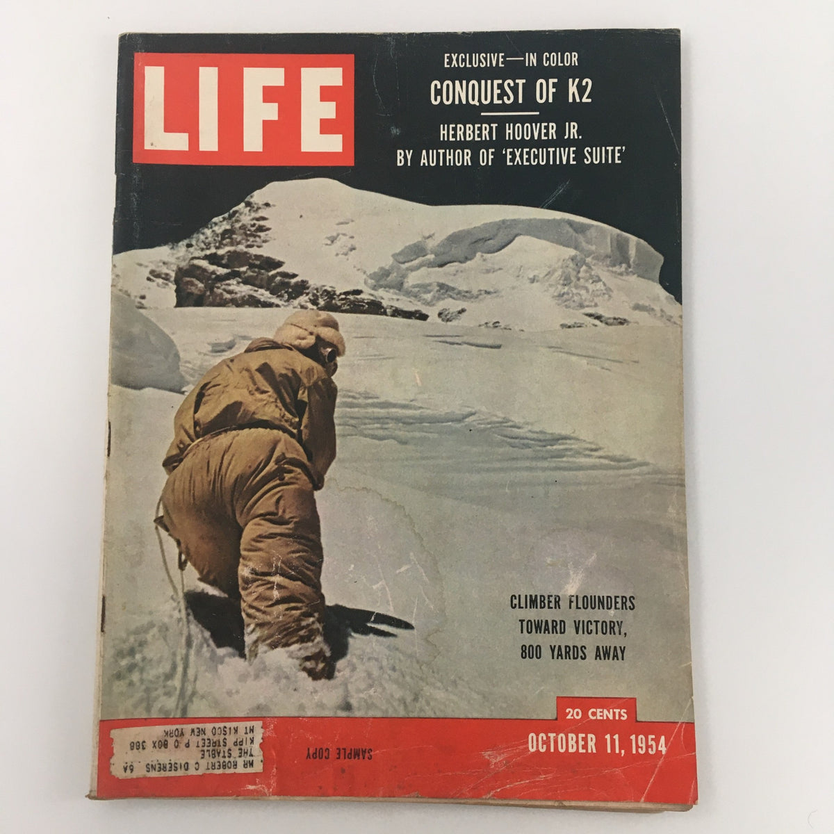 Cover of VTG Life Magazine from October 11, 1954, featuring the title 'Climber Founders Toward Victory, 800 Yards Away'. The magazine highlights an exclusive article on the Conquest of K2. The cover depicts a climber wearing winter gear in a snowy landscape.