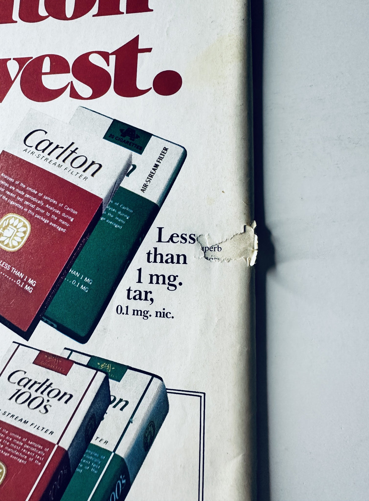 Close-up view of a vintage Carlton cigarette advertisement in Sports Illustrated Magazine March 3, 1980, emphasizing low nicotine and tar levels with the tagline 'The lighter 100's.'