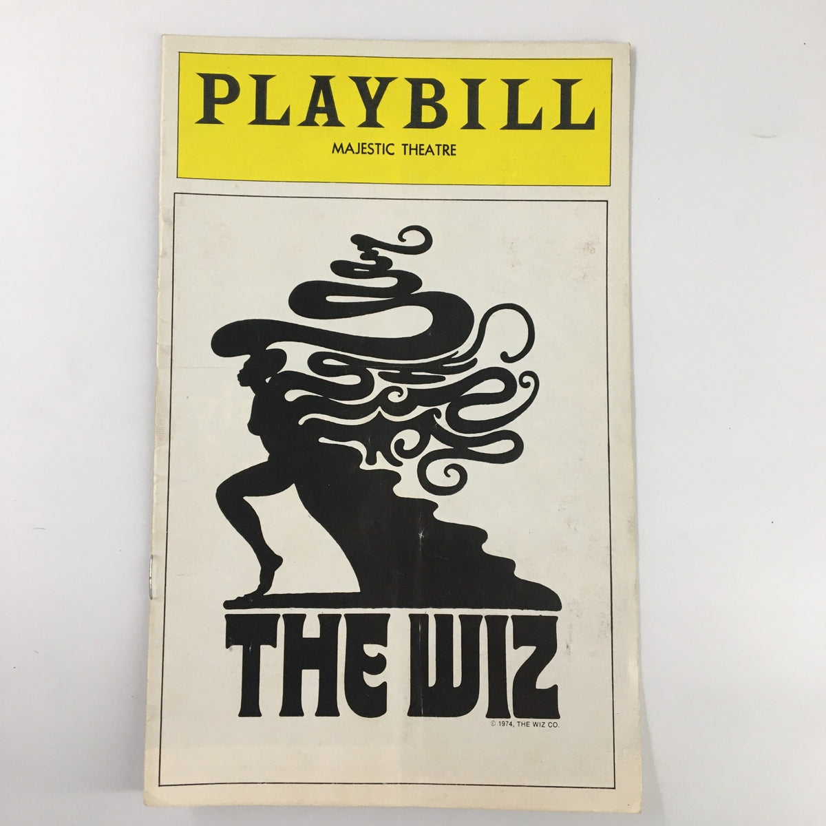 1975 Playbill for The Wiz at Majestic Theatre featuring an artistic design with flowing hair and silhouette of a figure. Good condition with minor wear, protected in plastic cover.