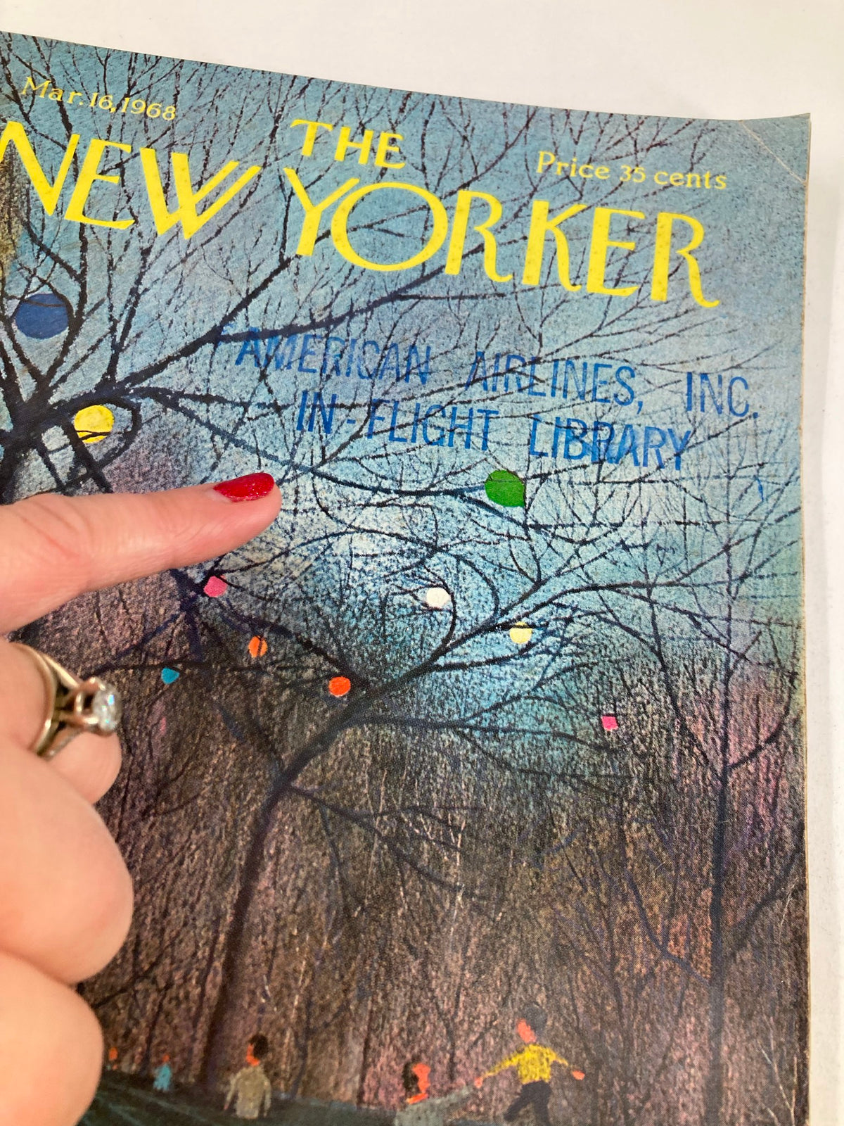 Close-up of The New Yorker Full Magazine March 16 1968 cover, highlighting the details of 'Bench Party' by C. E. Martin, with a finger pointing at the in-flight library title.