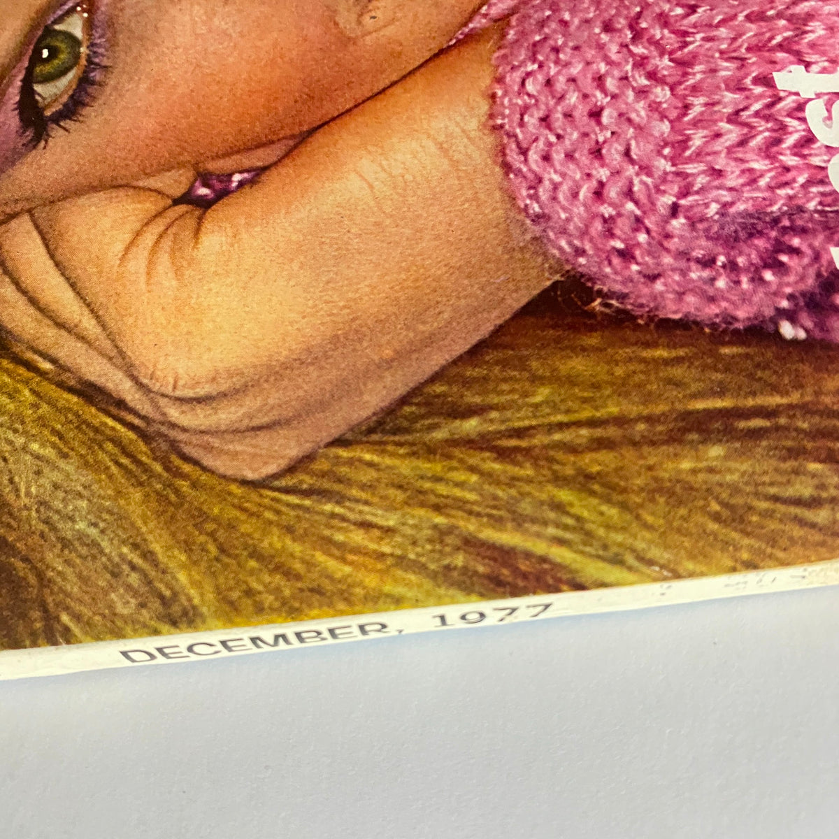 Close-up shot from Vogue Magazine December 1977 featuring a model with glamorous makeup and pink sweater, showcasing vintage fashion history.
