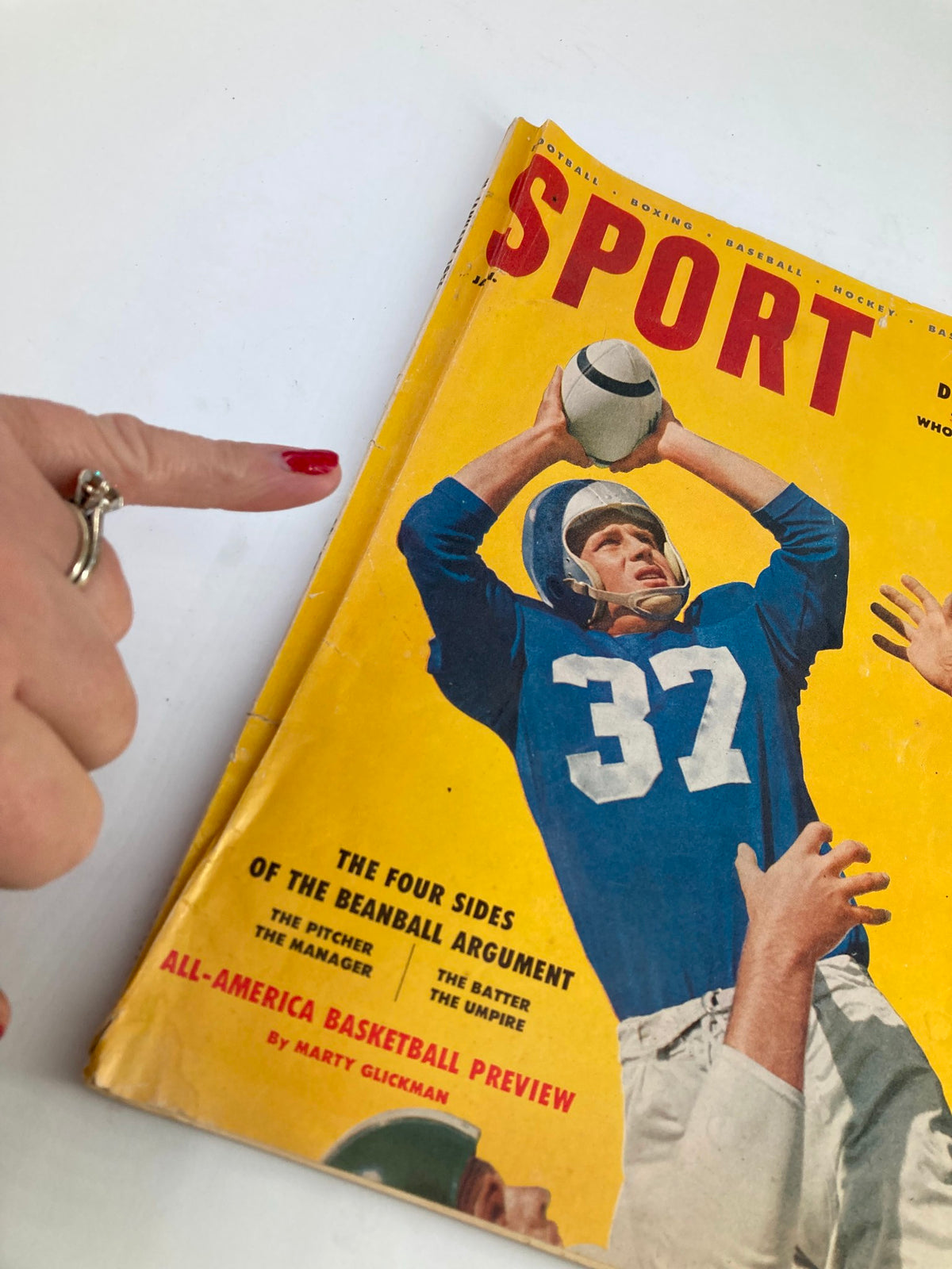 Close-up view of the cover of VTG Sport Magazine January 1956 Vol 21 #1, showing Doak Walker preparing to catch a football, with a finger pointing at the magazine.