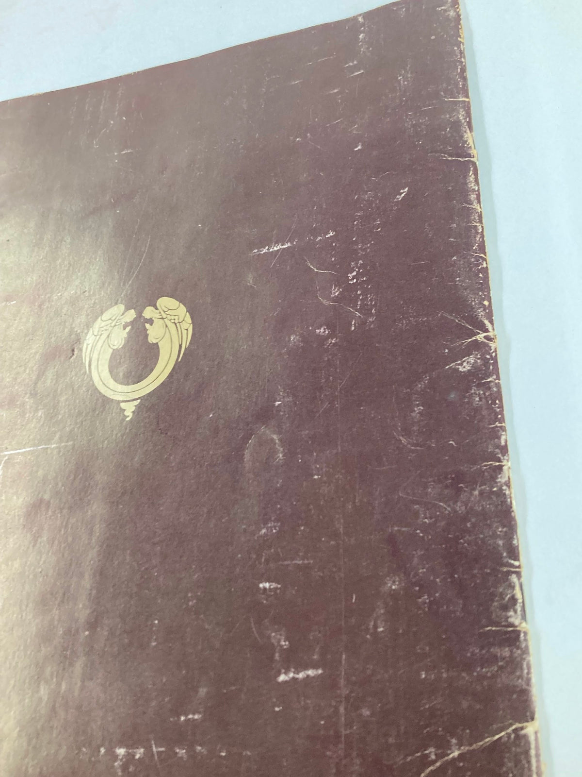 Close-up view of the back cover of the 1970 Jesus Christ Superstar Souvenir Program, highlighting wear and tear on the burgundy surface.