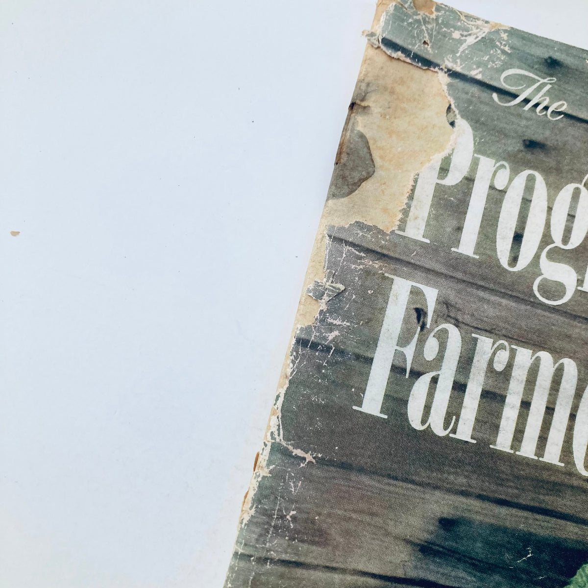 Close-up view of the partially torn cover of VTG The Progressive Farmer Magazine April 1958, showcasing the magazine's vintage charm and wear.