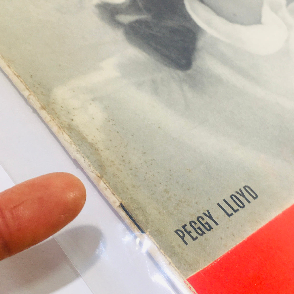 Close-up of the cover edge of the vintage magazine 'Life Magazine: May 24, 1943', featuring the name 'Peggy Lloyd' and showing signs of wear typical for its age, including a finger pointing at the magazine's surface.