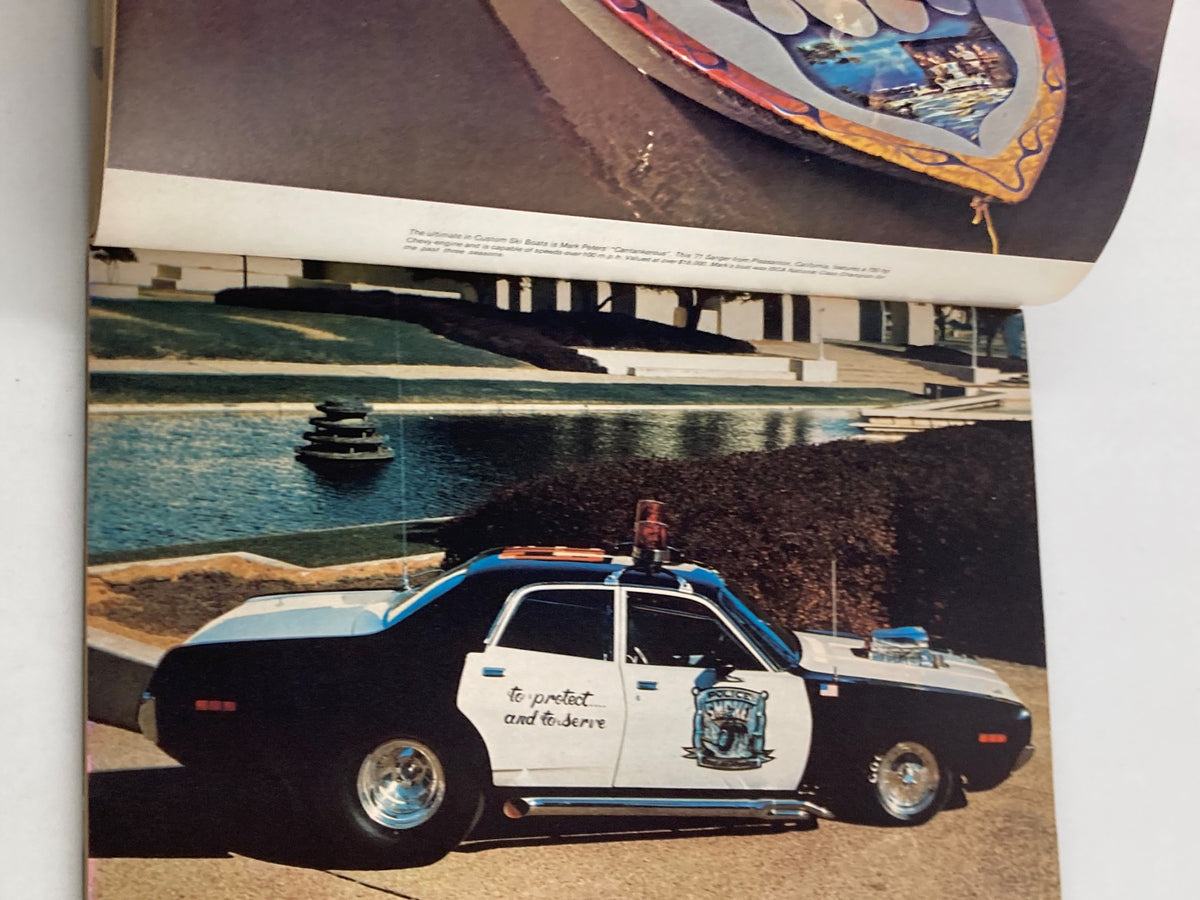 1976 Annual Spring Edition Hot Rod Showdown featuring a vintage police car parked near a serene pond, showcasing automotive culture.