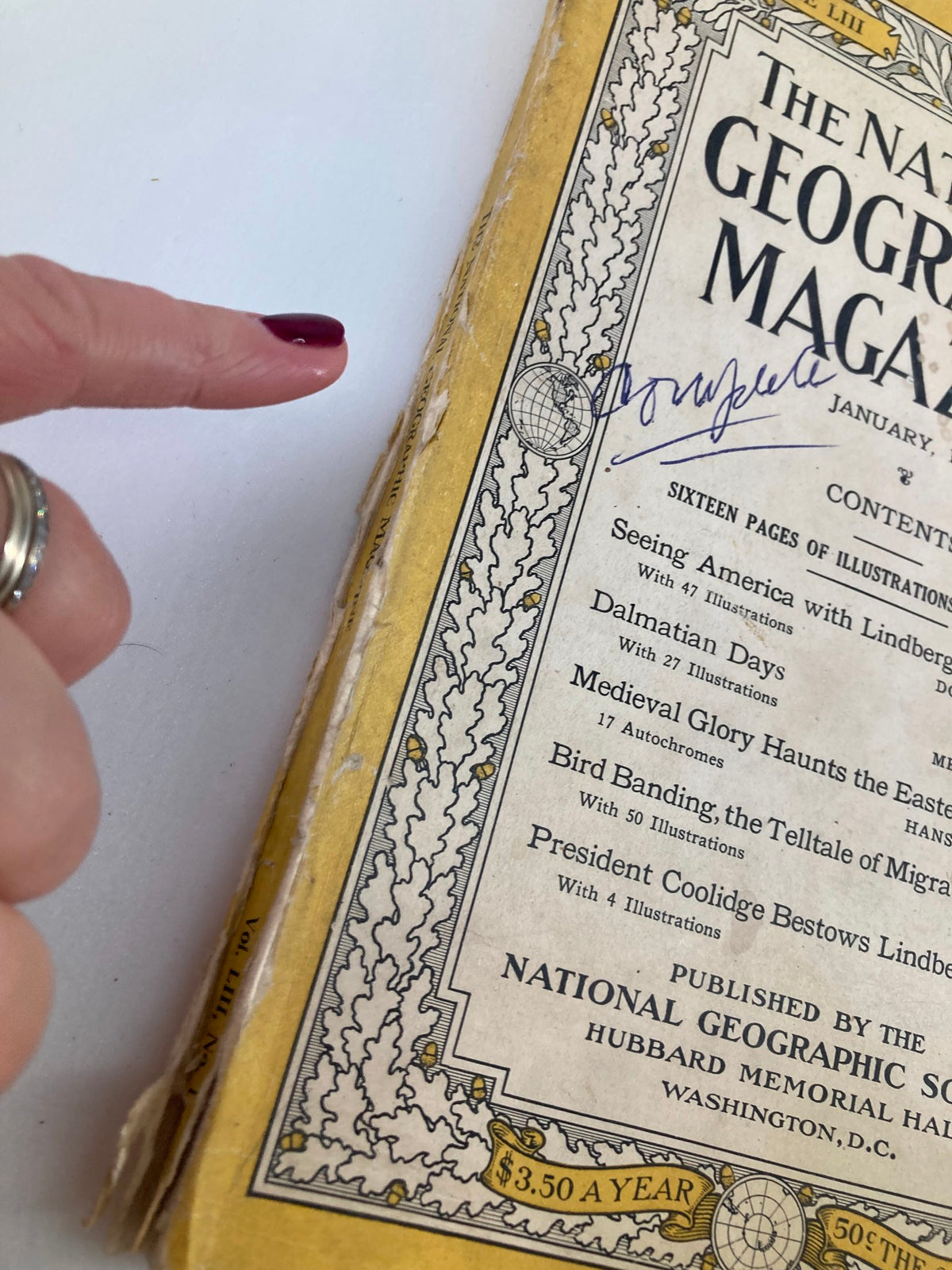 Close-up of the spine of the January 1928 National Geographic Magazine, showing minor wear and a handwritten signature, titled 'Dalmatian Days'.