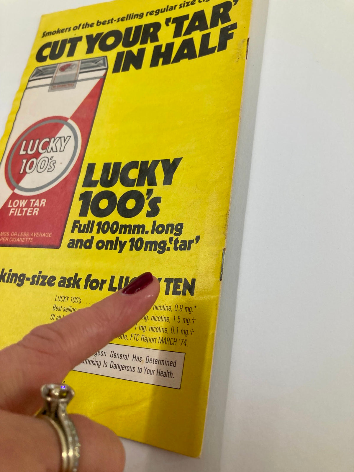 Back cover of the 1974 Playbill with a bright yellow advertisement for Lucky 100s cigarettes, featuring a woman's hand pointing to the product description.