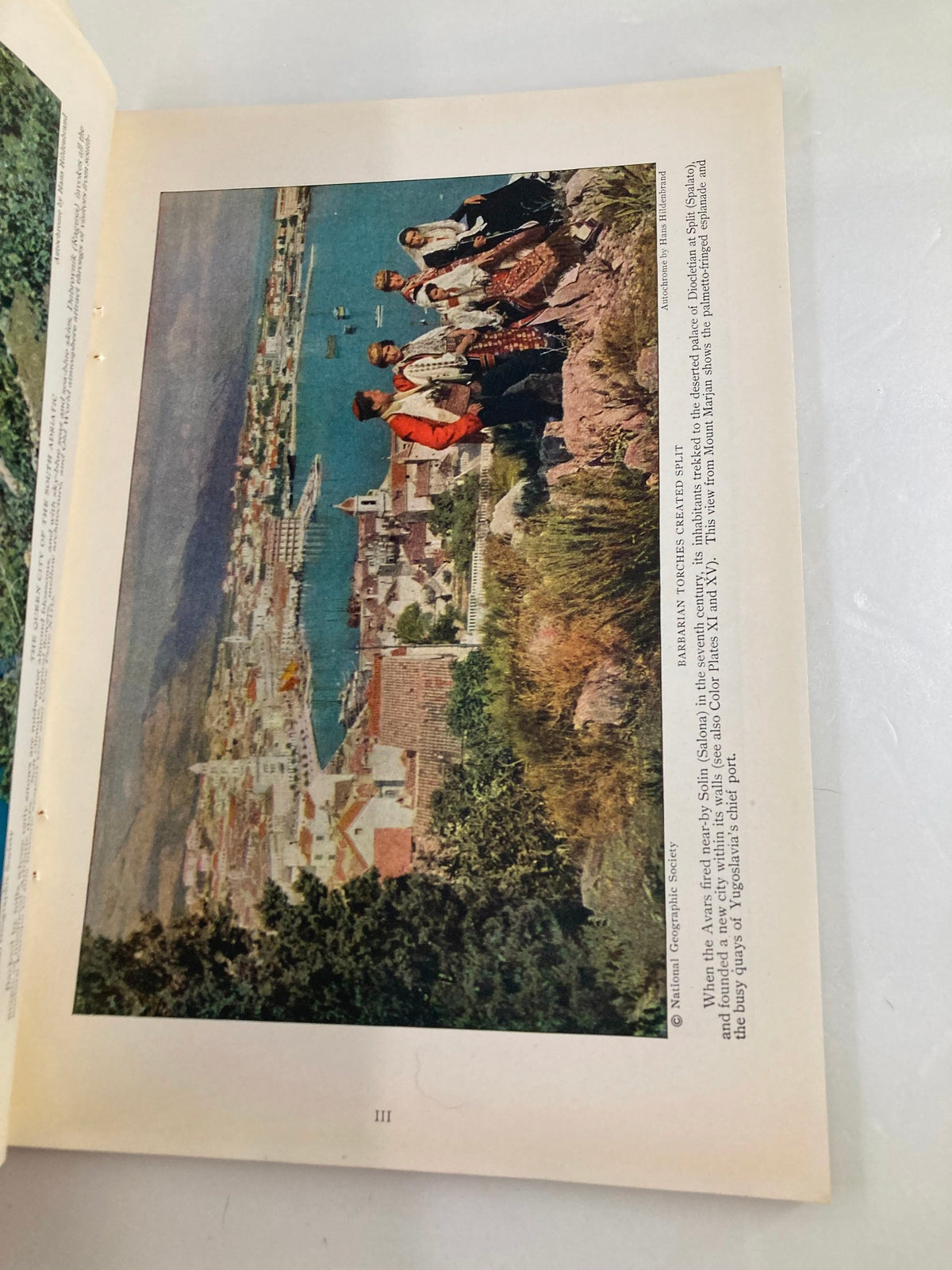 Another picturesque illustration from The National Geographic Magazine January 1928, capturing the beauty of a coastal landscape with figures in traditional dress, representing the era's focus on nature and culture.