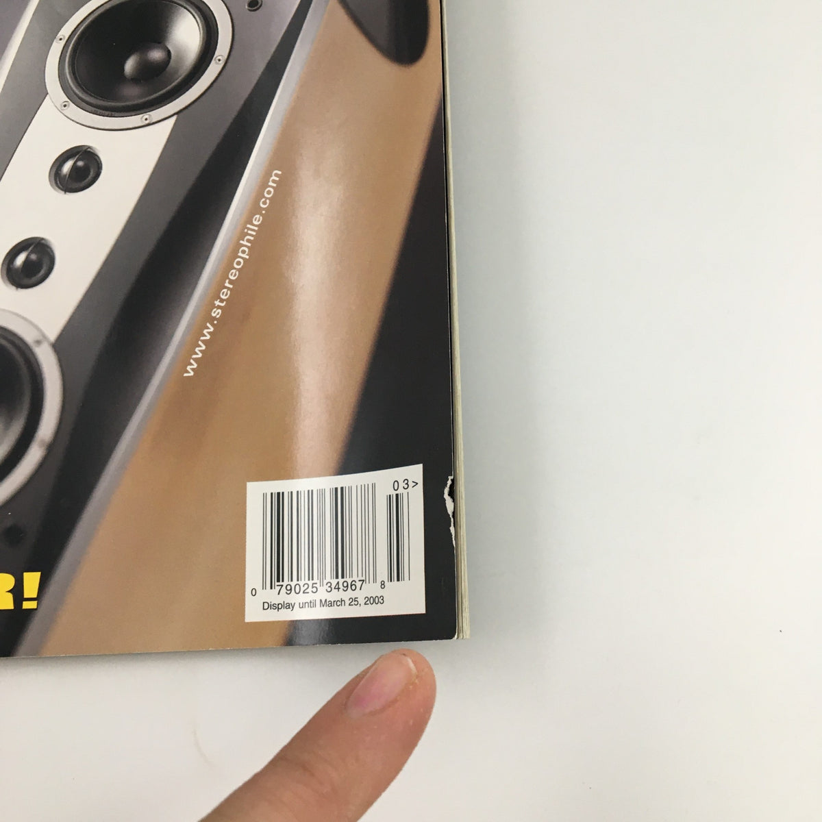 Back cover of Stereophile Magazine March 2003 featuring a barcode and a finger pointing at the pricing information, highlighting the magazine's collectible nature alongside Ry Cooder and Dynoaudio speaker.