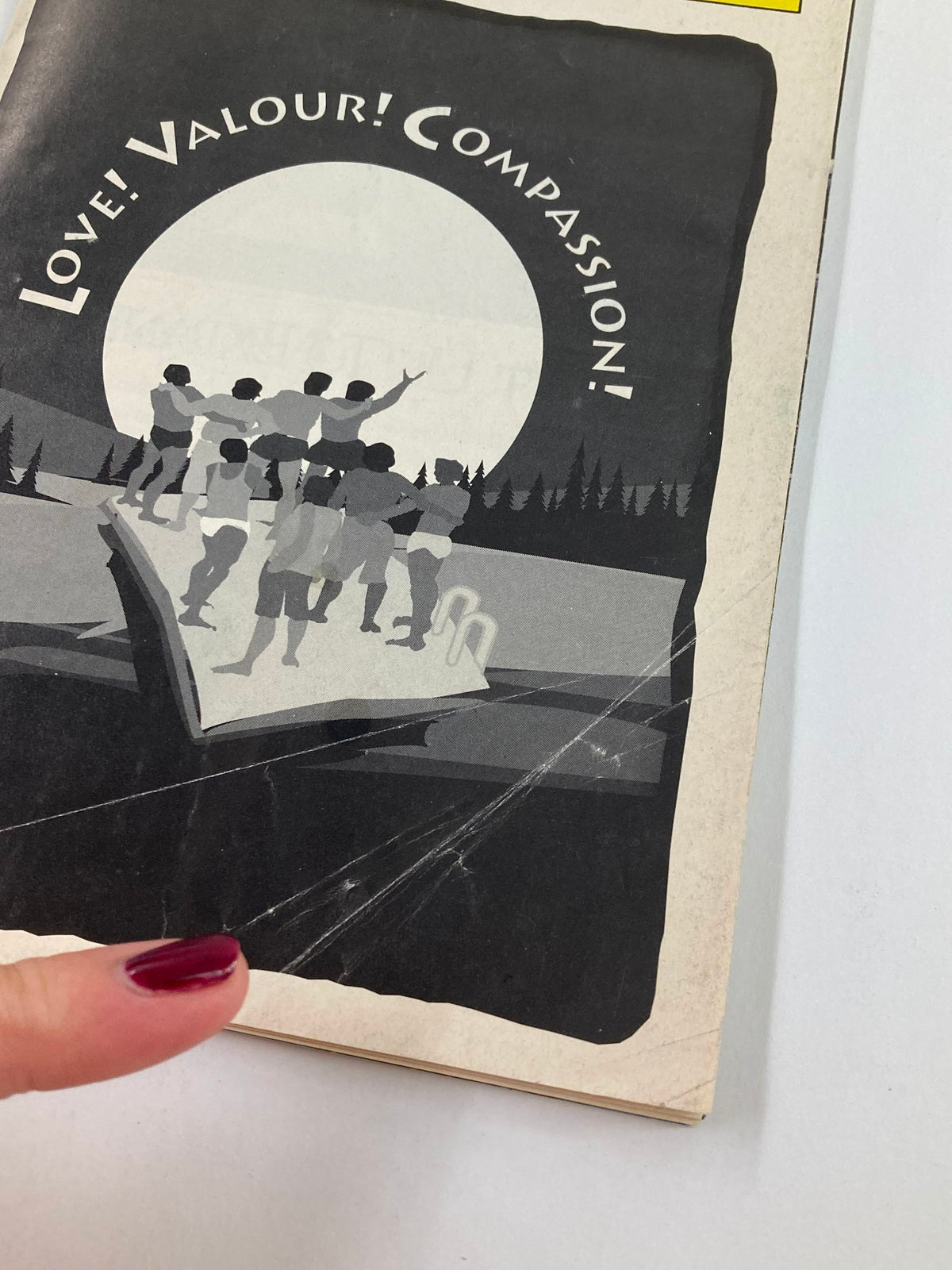 Close-up of the 1995 Playbill for Love! Valour! Compassion! showing the cover and highlighting a scratch on the surface.