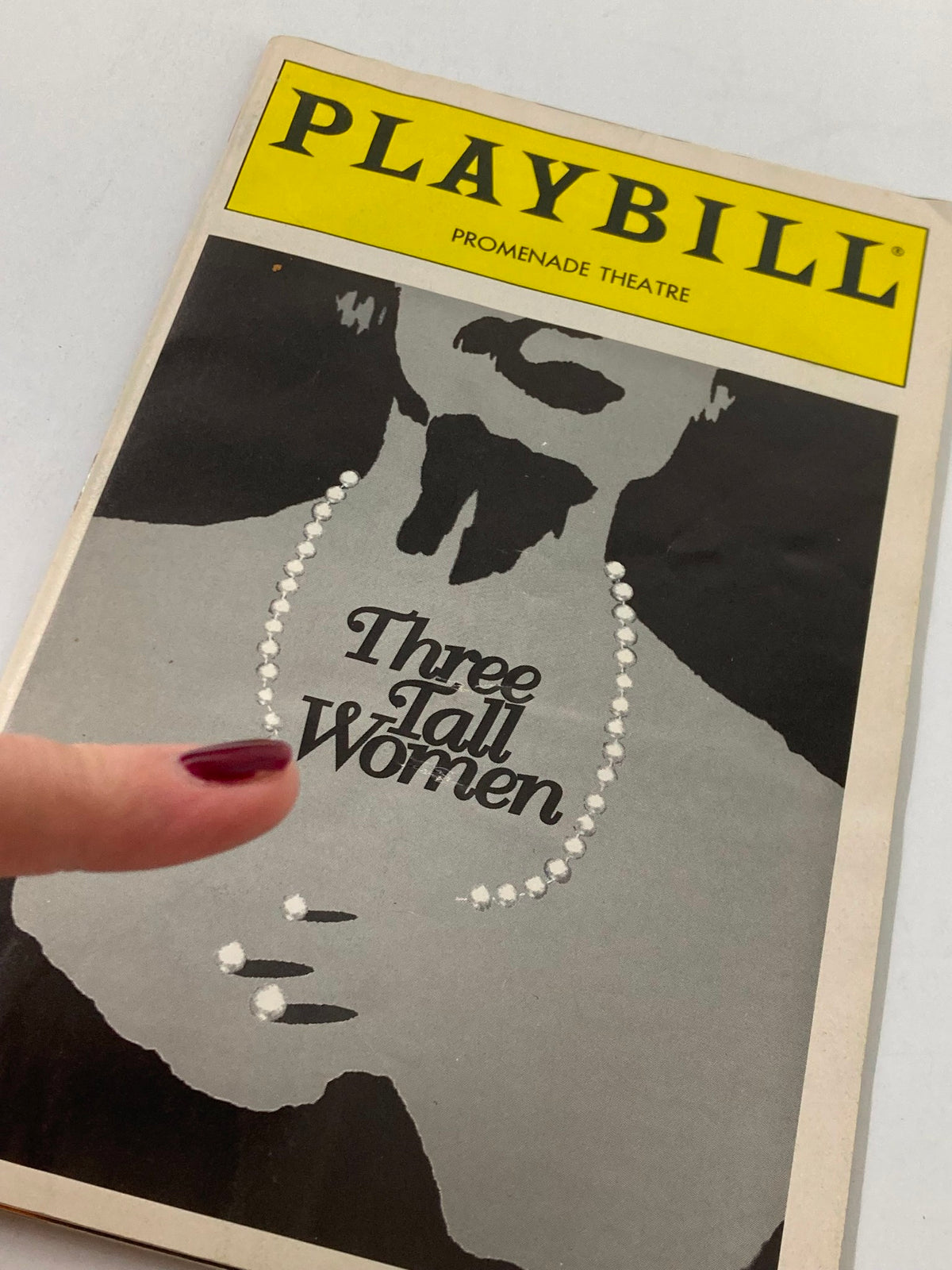 Close-up of the 1995 Playbill for Edward Albee's Three Tall Women, highlighting the cover design and title with a finger pointing at it.