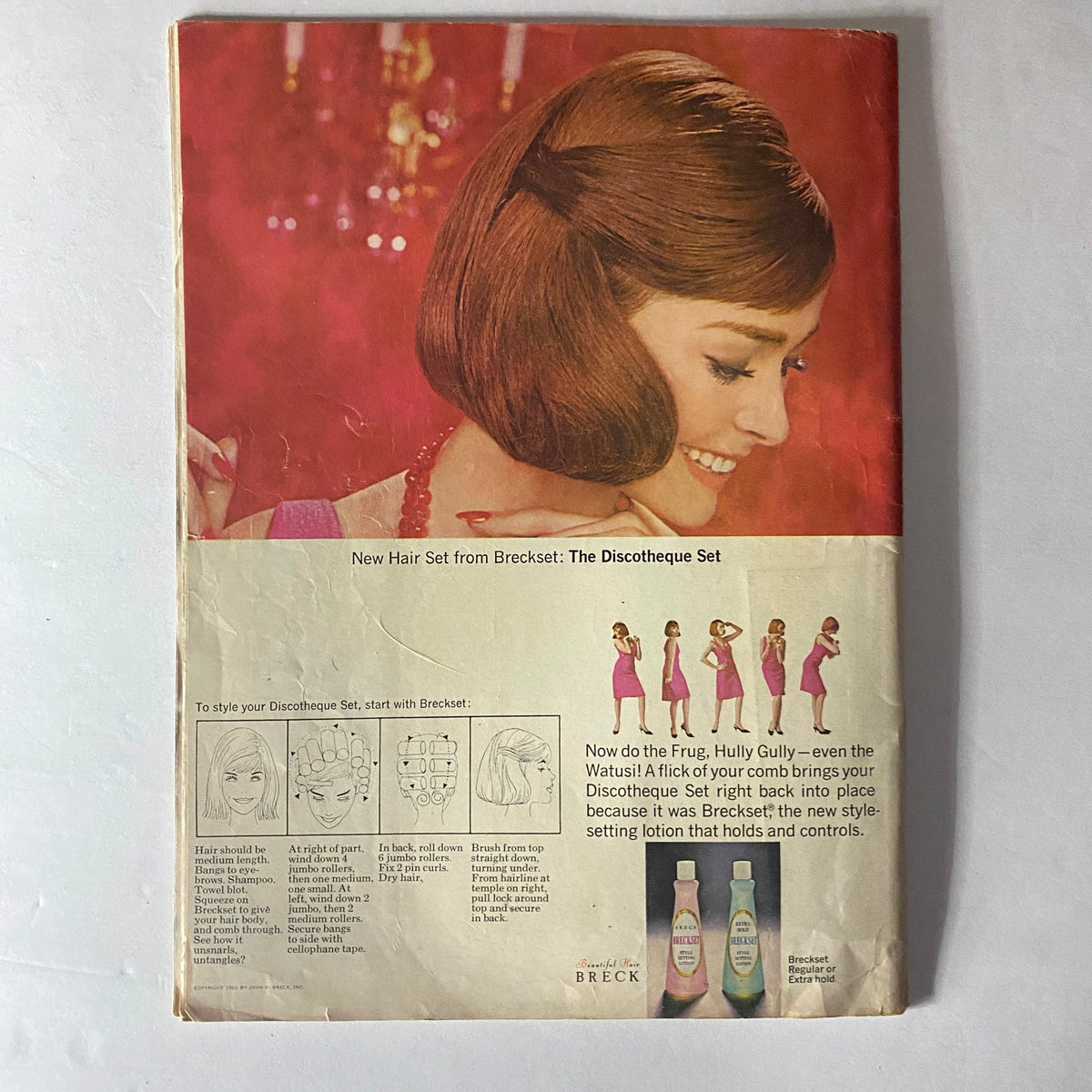 Cover of American Girl Magazine February 1965 featuring an advertisement for the Breck Discotheque Set. The magazine showcases a stylish model with elegant hair against a vibrant pink background, illustrating beauty trends of the 1960s.