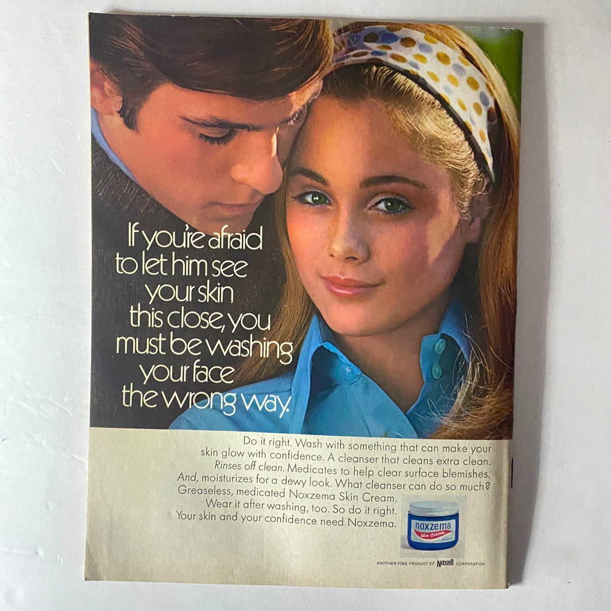 Advertisement from American Girl Magazine December 1969 for Noxzema Skin Cream, showcasing a young couple and promoting skincare confidence.