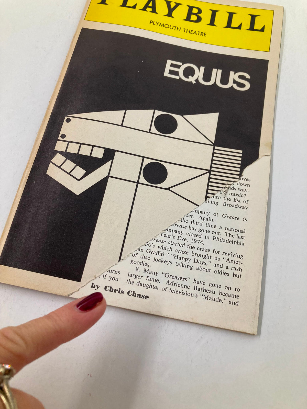 Close-up of the 1976 Vol 120 #1 Playbill featuring Anthony Perkins in Equus at Plymouth Theatre, with focus on the unique horse head design and a hand pointing to the cover.