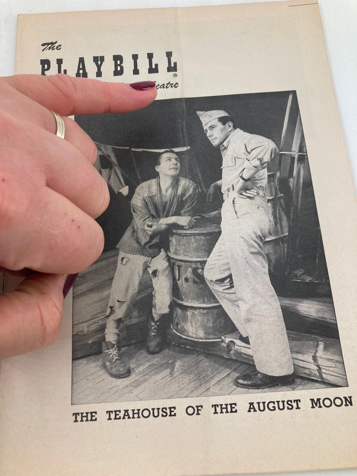 Close-up view of the 1954 Playbill for The Teahouse of the August Moon, showing a black and white image of two characters, one in military uniform and the other in casual attire, highlighting their interaction.