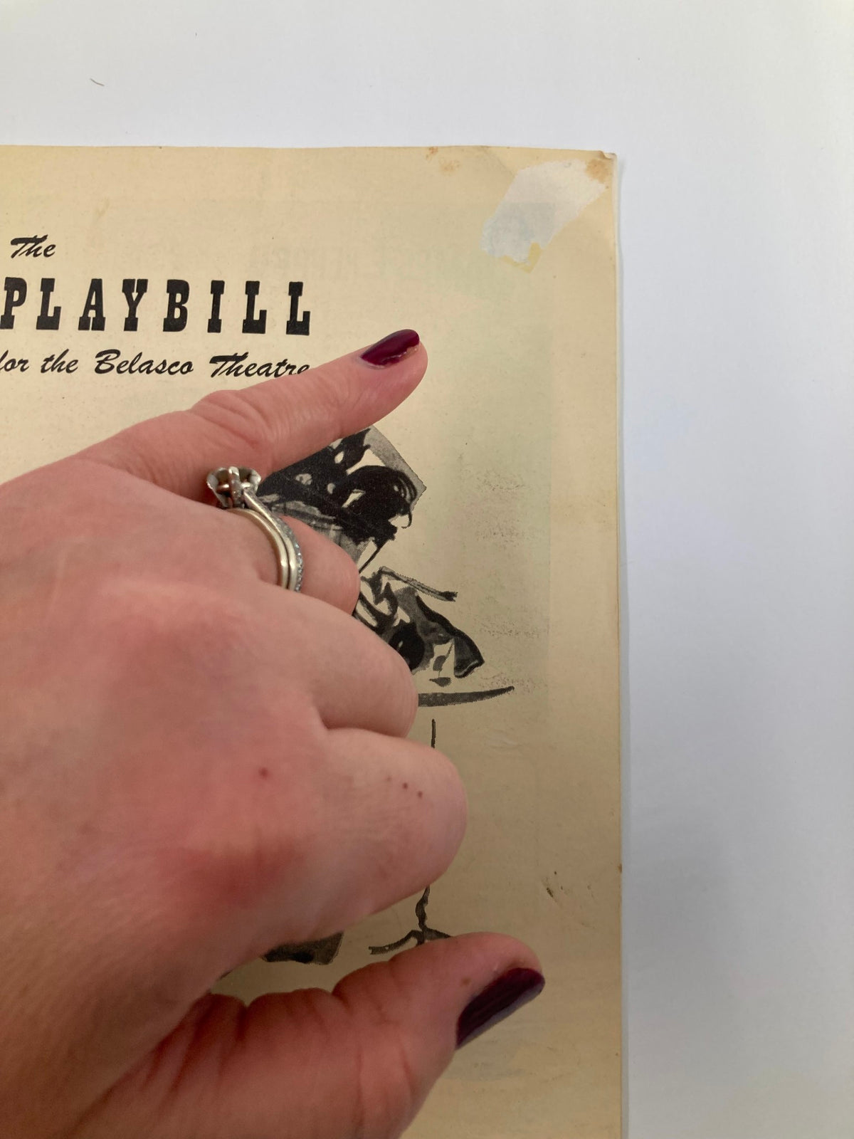 Detail view of the 1949 Playbill for the Belasco Theatre, highlighting the cover illustration of The Madwoman of Chaillot with a hand pointing to a minor damage at the corner.