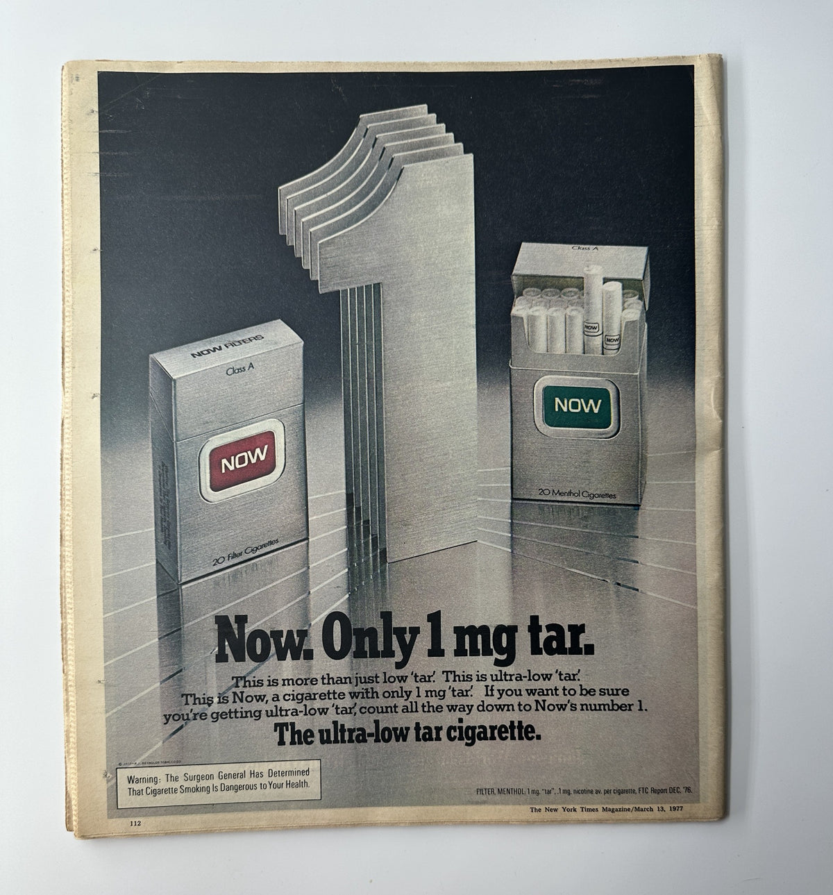 Advertisement for Now cigarettes featuring the slogan 'Now. Only 1 mg tar.' The image showcases packs of Now cigarettes with an emphasis on its low tar content, illustrating health considerations related to smoking. Title: The New York Times Magazine March 13, 1977 Golden Clan Irish Society VG.