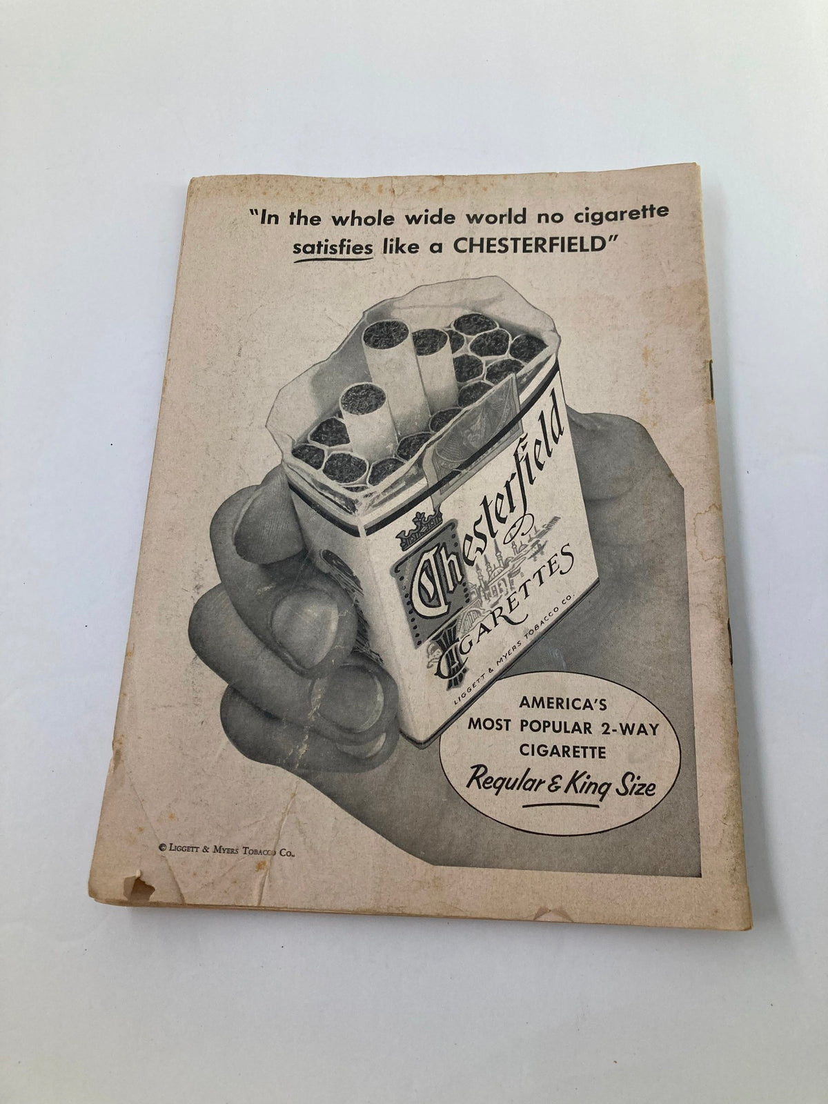 Vintage advertisement for Chesterfield cigarettes, featuring a hand holding a pack, with the slogan 'In the whole wide world no cigarette satisfies like a CHESTERFIELD.' This advertisement reflects mid-20th century tobacco marketing.