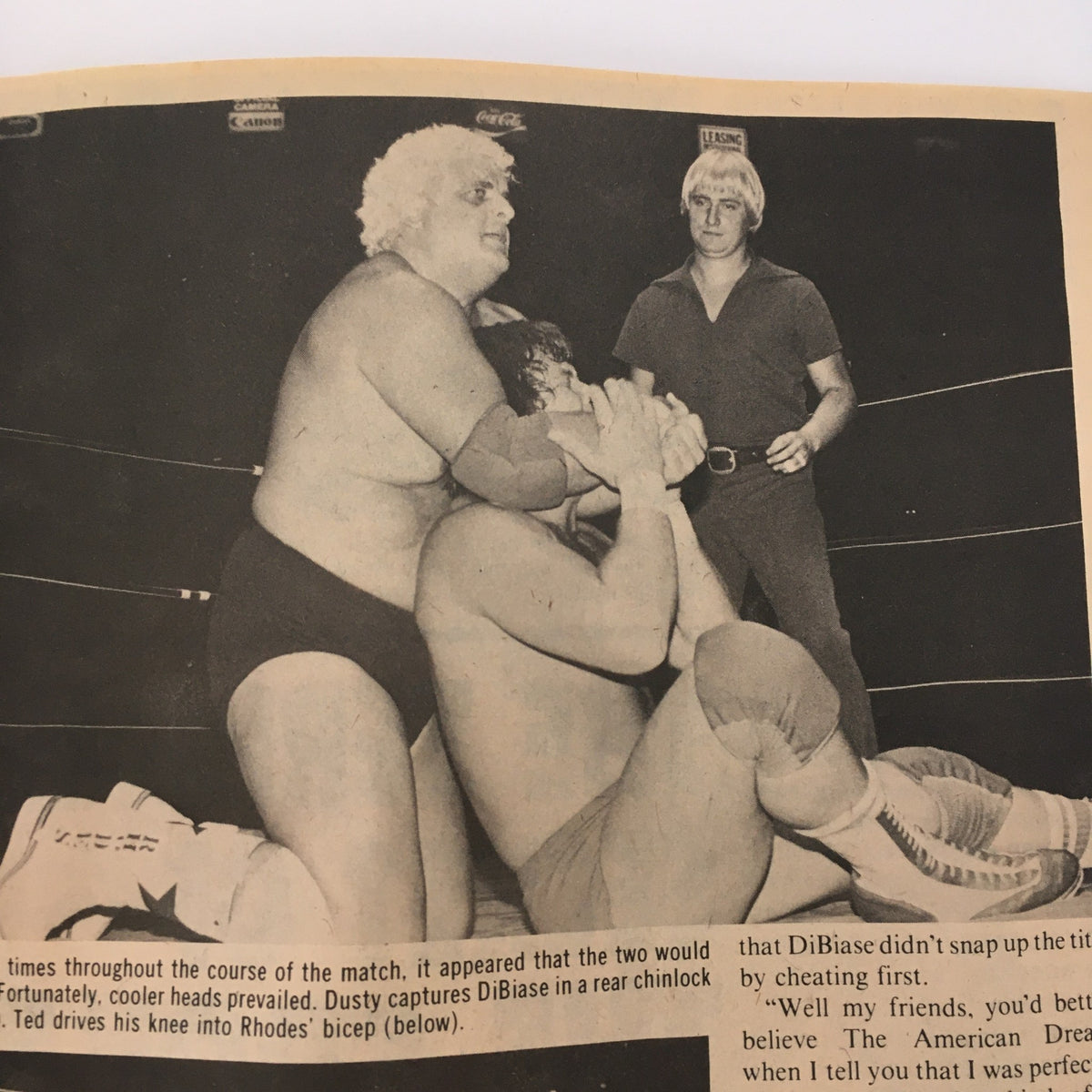 Black and white image from a wrestling match showing Dusty Rhodes in a rear chinlock. Sports Review Wrestling Magazine November 1981.