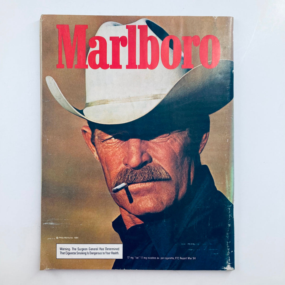 Marlboro Magazine cover featuring a rugged cowboy in a white hat with a cigarette, representing classic American culture in advertising, shown alongside VTG Playboy Magazine April 1985.