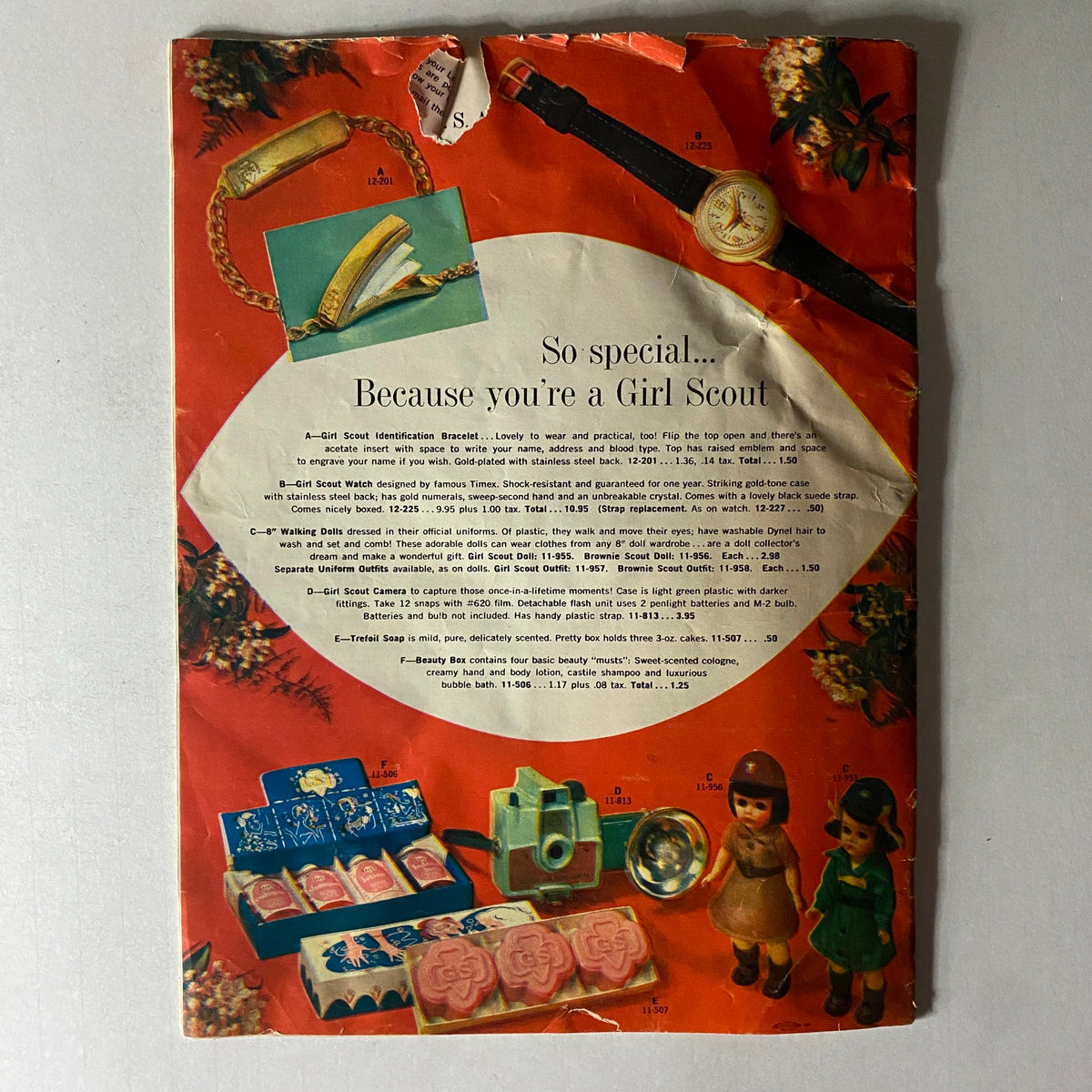 Back cover of the Girl Scout Equipment Fall 1959 Spring 1960 Catalog featuring a variety of Girl Scout memorabilia, including a watch, bracelet, and dolls, emphasizing the collectibles from that era.