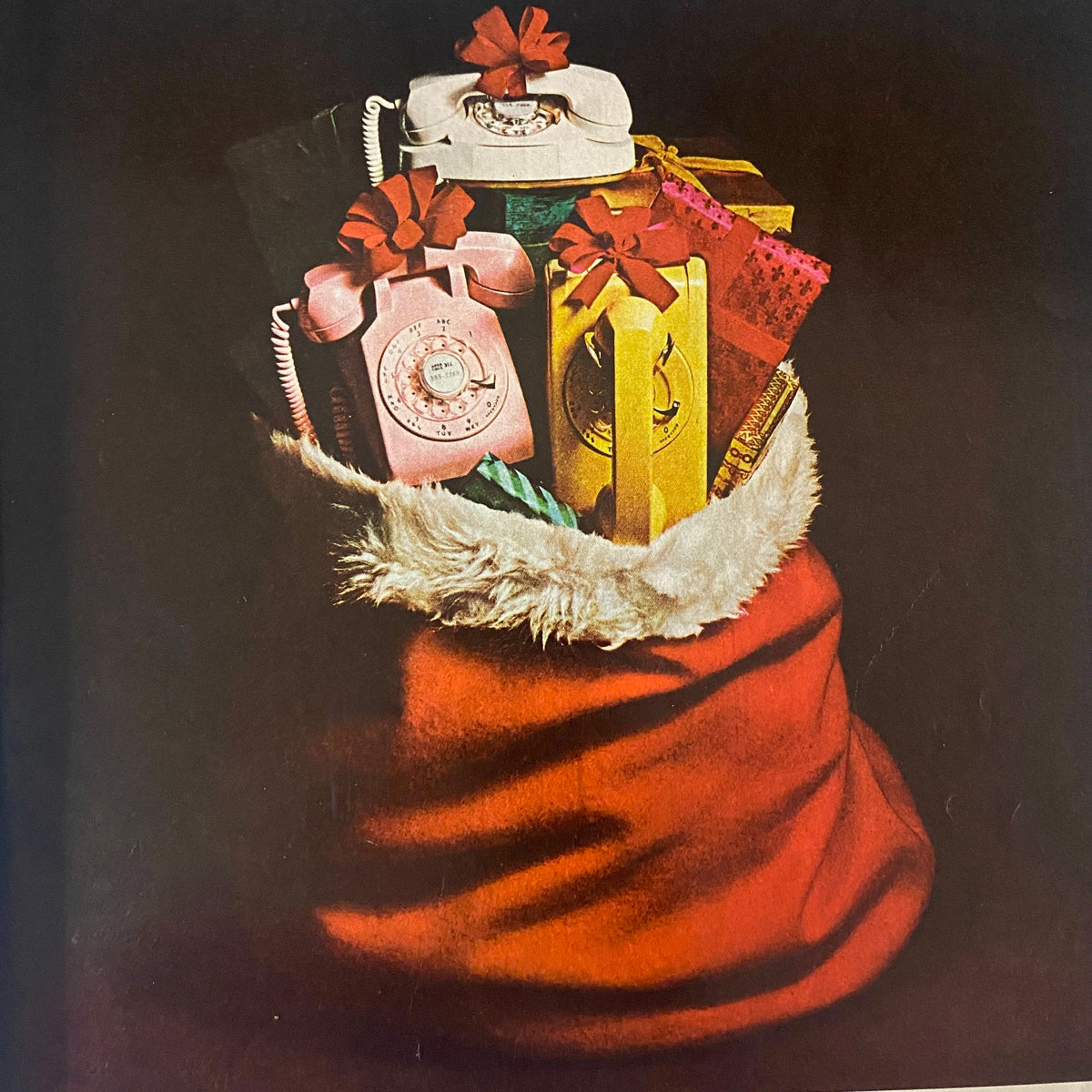 Festively arranged Christmas gifts and a vintage telephone in a red Santa sack, featured in Better Homes & Gardens Magazine December 1963 Christmas Issue.