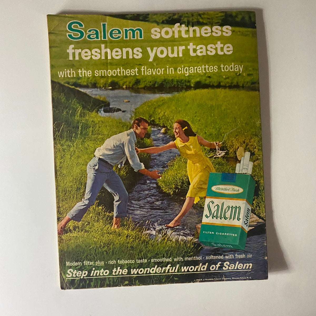 Vintage advertisement featuring a couple enjoying nature next to a creek, promoting Salem cigarettes, included in Better Homes & Gardens Magazine December 1963 Christmas Issue.