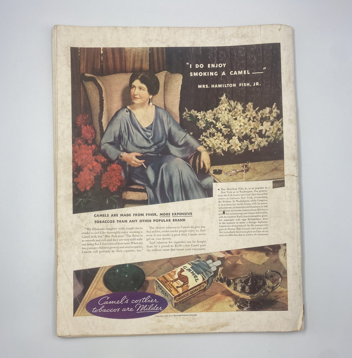Vintage advertisement featuring Mrs. Hamilton Fish, Jr. enjoying a Camel cigarette. The image is from the December 1933 issue of Woman’s Home Companion Magazine with the title 'Christmas Bright with Peril'. The background includes flowers and decorative elements, emphasizing the elegance of the time.