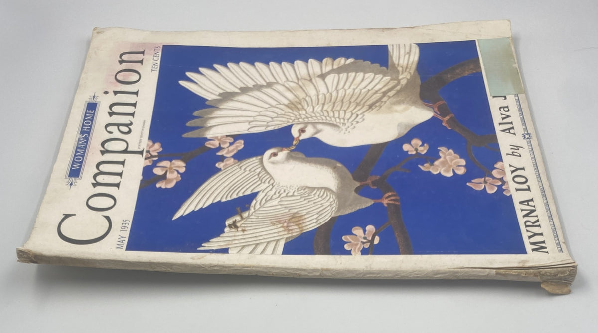 Side view of Woman’s Home Companion Magazine May 1935 displaying the cover design with white doves and purple flowers. Features Myrna Loy's name prominently, illustrating classic magazine aesthetics.