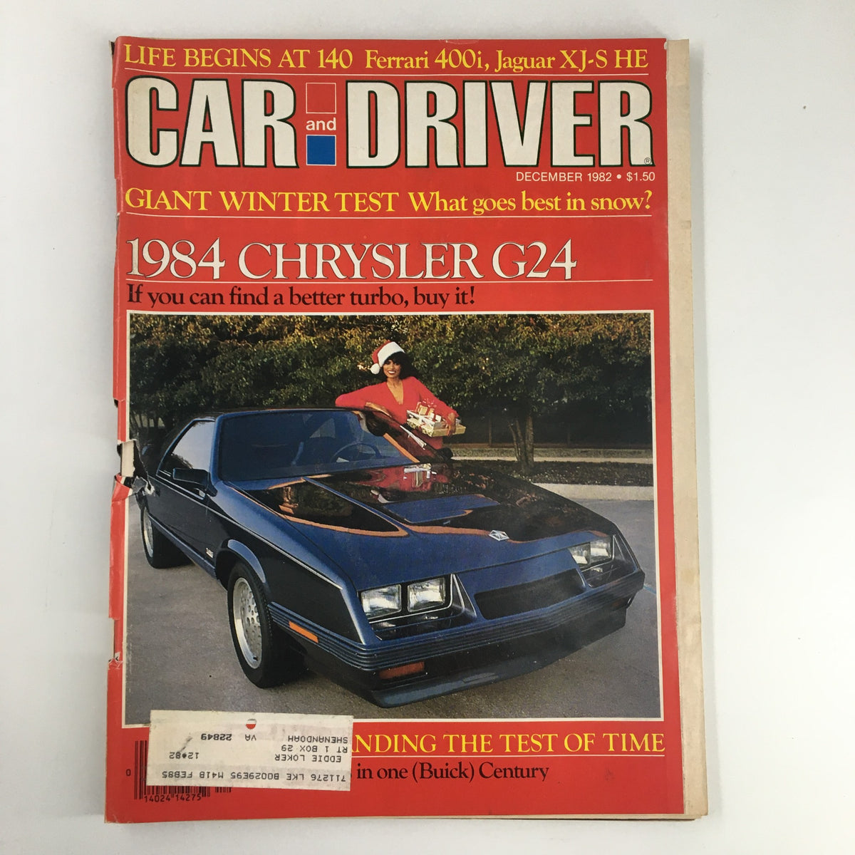 Cover of Car and Driver Magazine December 1982 featuring the 1984 Chrysler G24 and the 140 Ferrari 400i, showcasing a woman in a red outfit with Christmas gifts beside a black Chrysler.