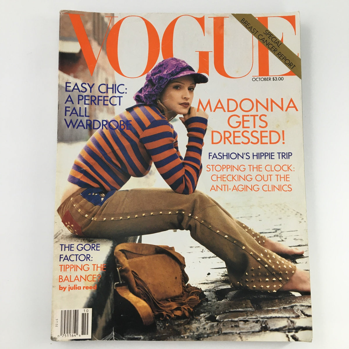 Cover of Vogue Magazine from October 1992 featuring Madonna, with the headline 'Madonna Gets Dressed!' The image shows a model in a striped sweater and a purple hat, sitting on a sidewalk, showcasing a perfect fall wardrobe.