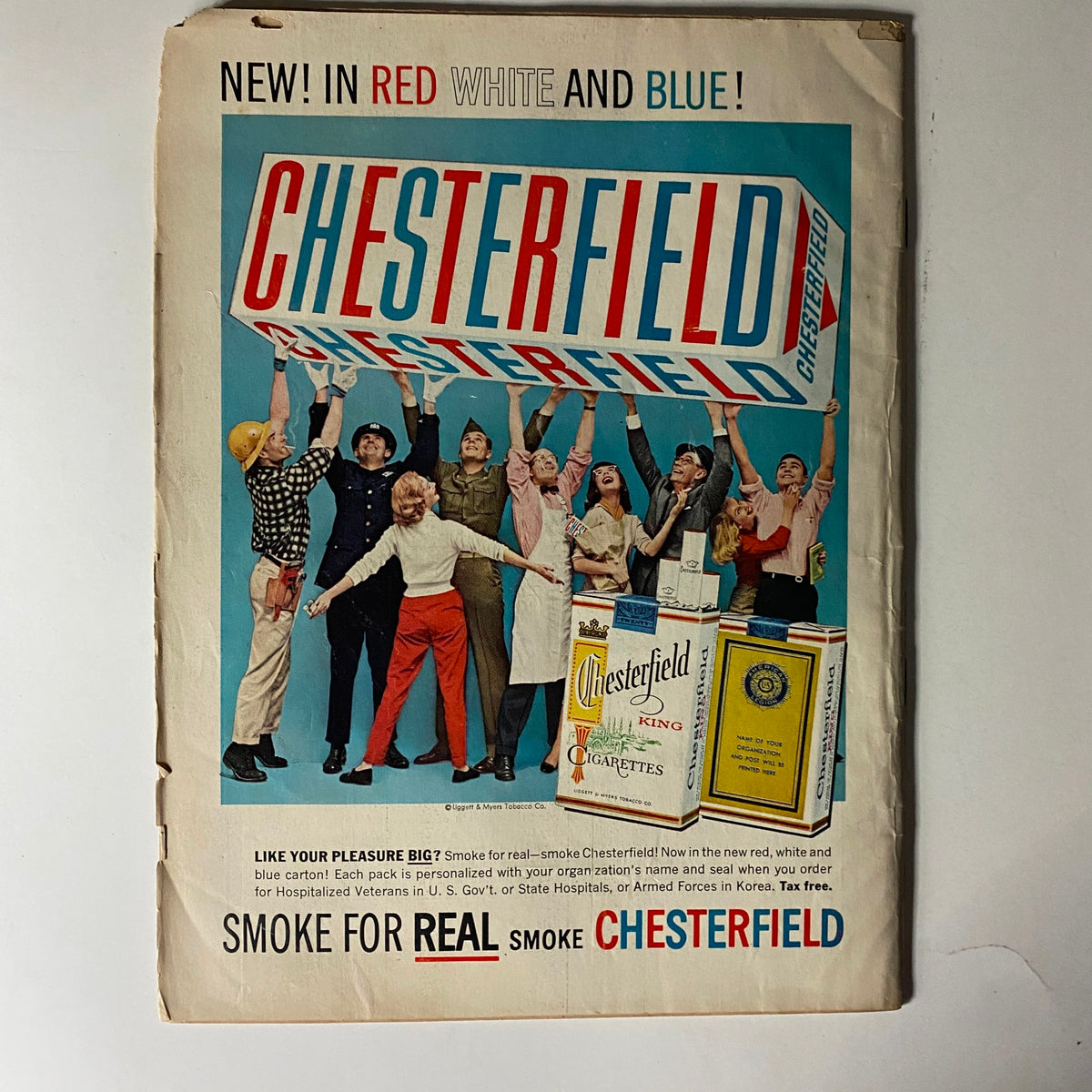 Advertisement on the back cover of The American Legion Magazine, July 1957, promoting Chesterfield cigarettes, featuring a colorful illustration of diverse individuals celebrating and presenting a new cigarette offering in a patriotic theme.