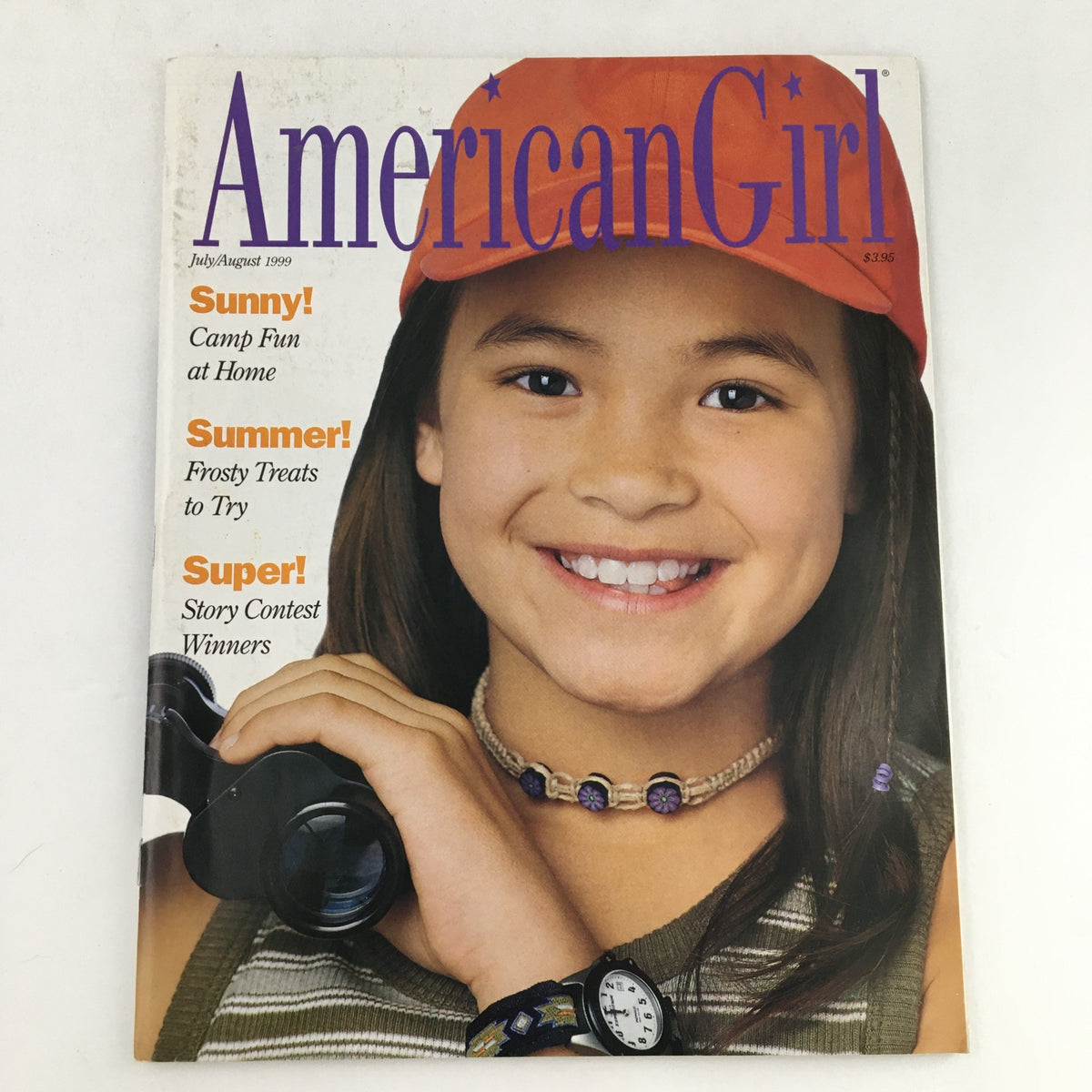 Cover of American Girl Magazine July-August 1999 featuring a smiling girl with a camera, showcasing summer themes including frosty treats, camp fun, and story contest winners.