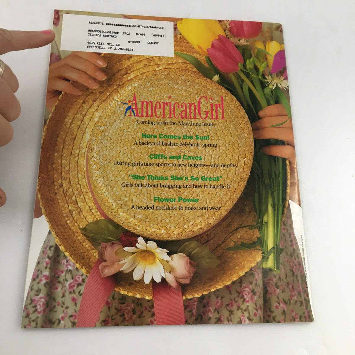 Back cover of American Girl Magazine March-April 1997, showcasing a straw hat adorned with flowers and a list of upcoming articles in the May-June issue, connecting to themes of creativity and empowerment.