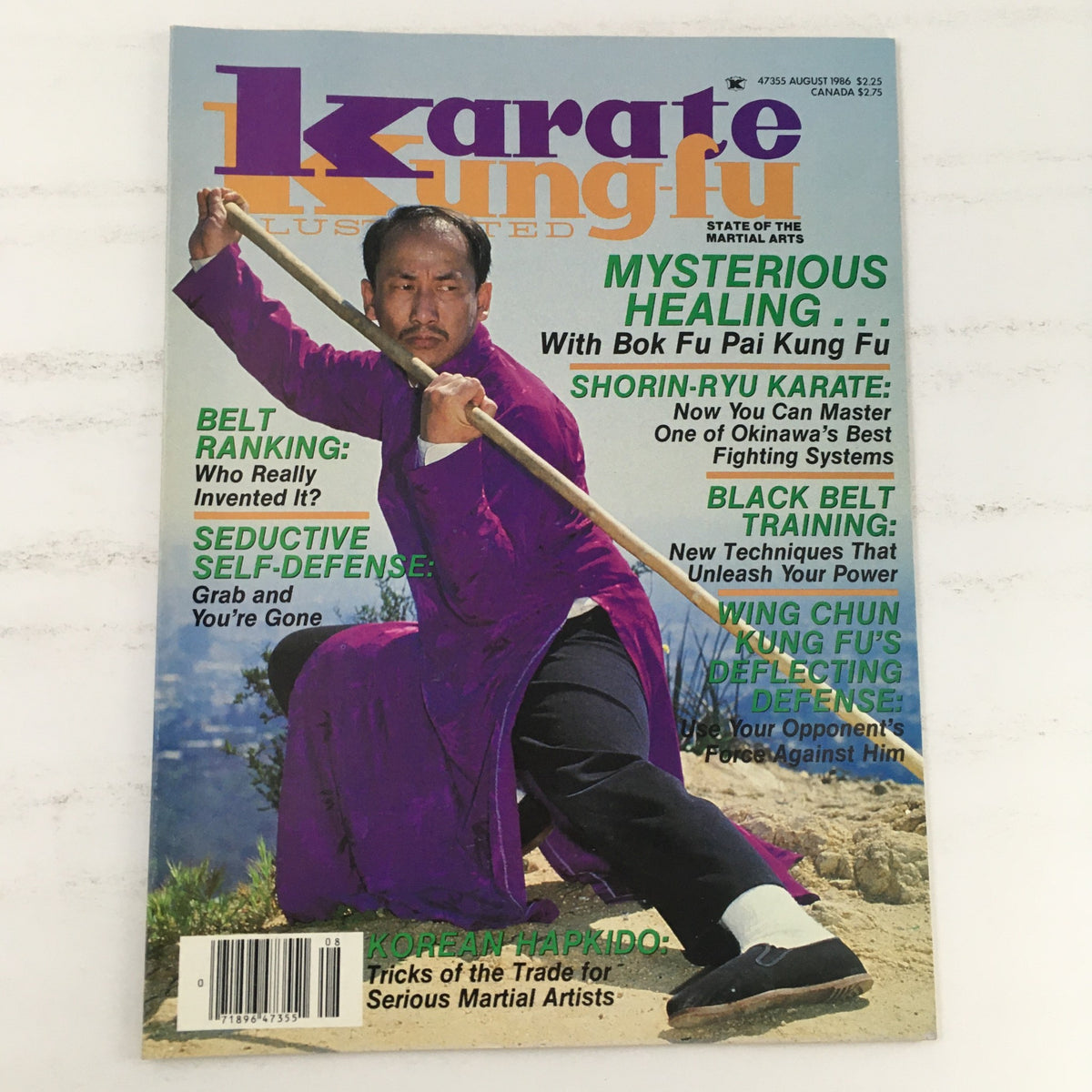 Cover of Karate Kung-Fu Illustrated Magazine August 1986 Vol 17 #8 featuring a martial artist in a purple outfit demonstrating a martial arts stance with stick. The cover highlights various topics including Mysterious Healing, Shorin-Ryu Karate, Black Belt Training, and more.
