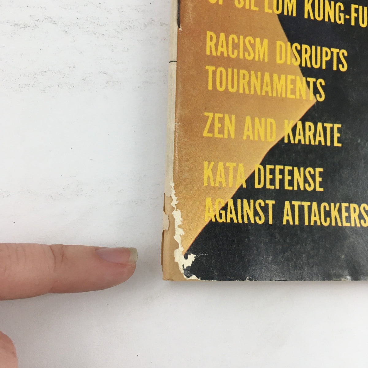 Close-up view of the spine of 'Karate Illustrated Magazine May 1971 Vol 2 #5 Featuring Leo Fong & Robert Garvey'. The image showcases the condition of the magazine, emphasizing visible wear and the titles of featured articles such as 'Zen and Karate' and 'Kata Defense Against Attackers'.