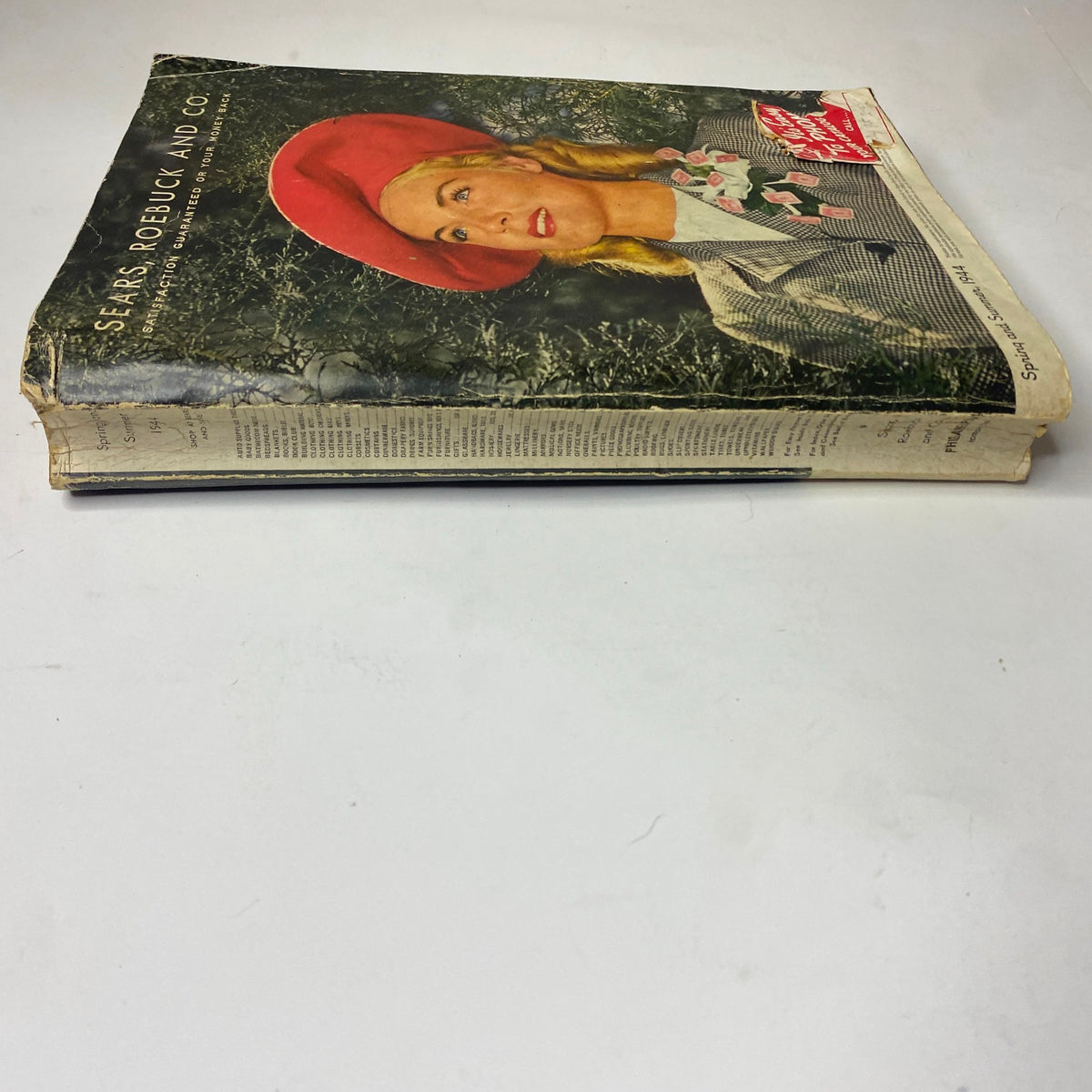 1944 Sears, Roebuck and Co. Spring and Summer Catalog featuring a side view of the catalog, highlighting its vintage appeal and worn condition, a testament to its historical significance.